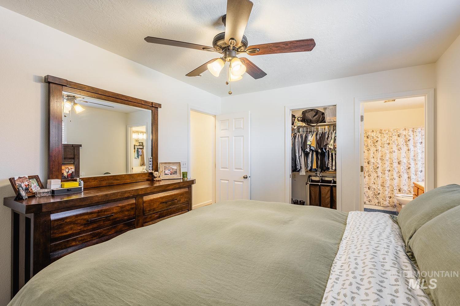 Carpeted bedroom featuring connected bathroom, a ceiling fan, a spacious closet, and a textured ceiling