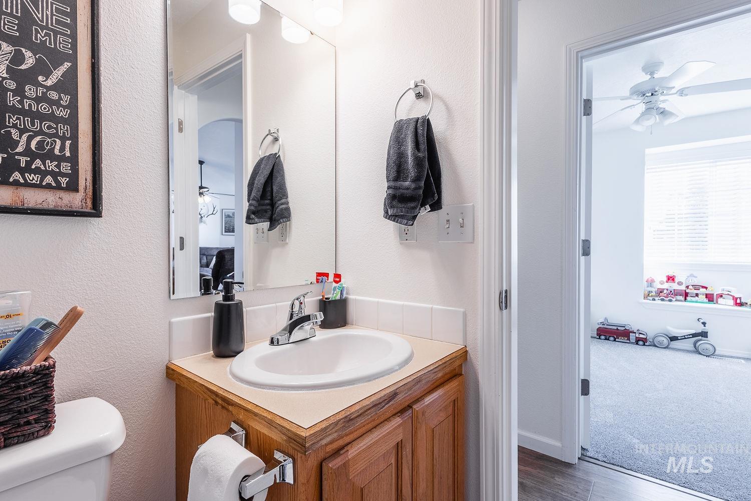 Bathroom with ceiling fan, vanity, and dark wood-style floors