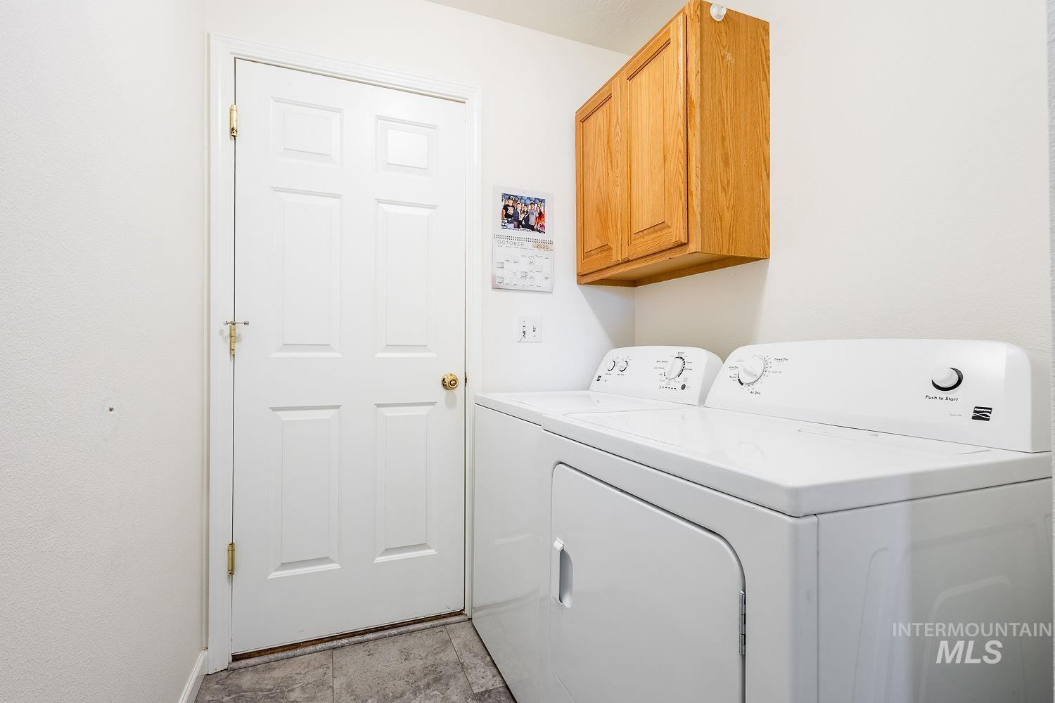 Laundry room with cabinet space, washing machine and clothes dryer, and light tile patterned flooring