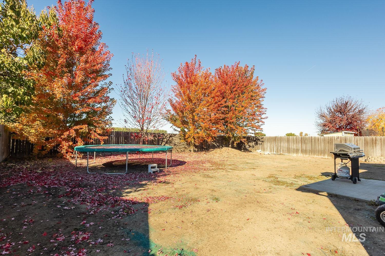 Fenced backyard featuring a trampoline