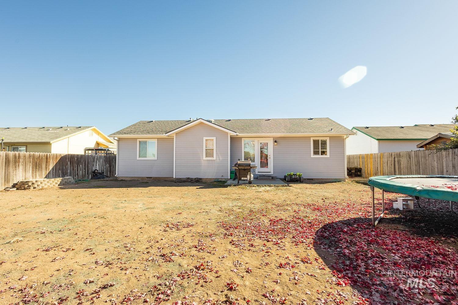 Back of property featuring a patio, a fenced backyard, and a trampoline