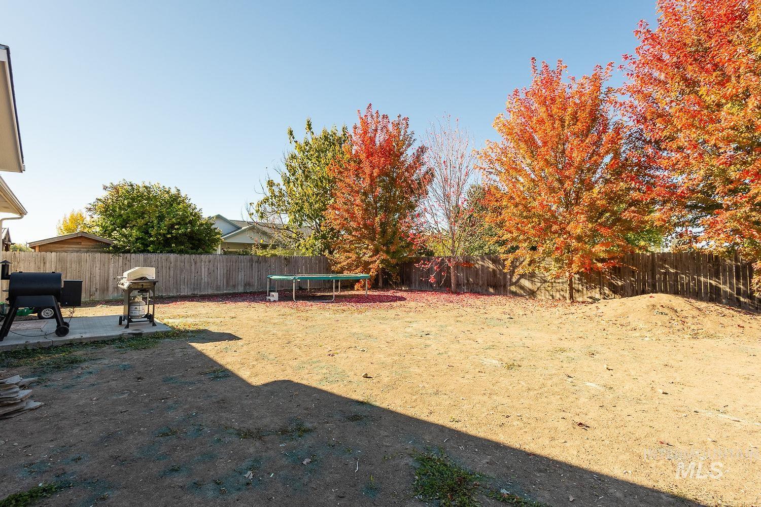 Fenced backyard with a trampoline and a patio