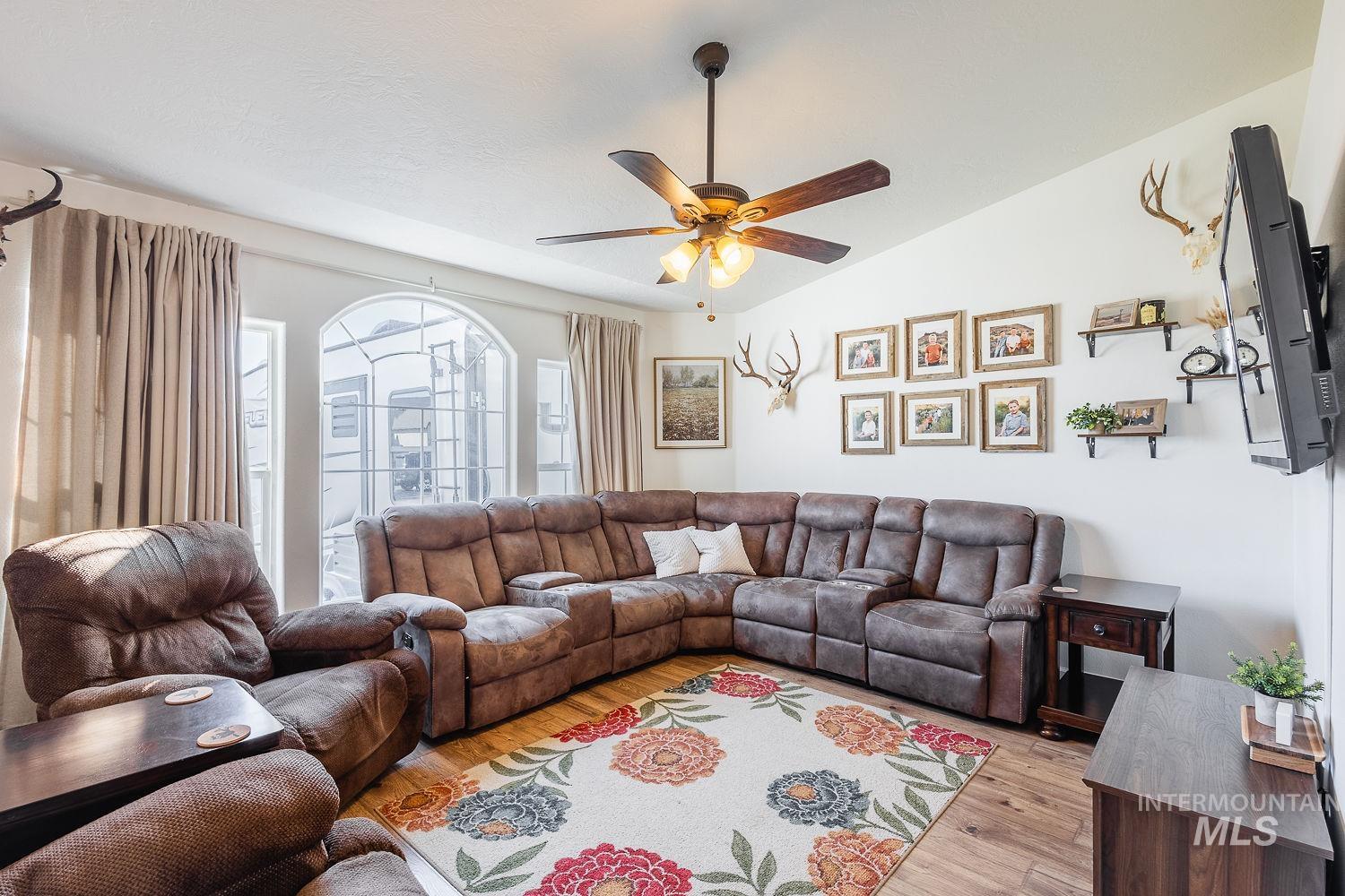 Living area with wood-type flooring, vaulted ceiling, and ceiling fan