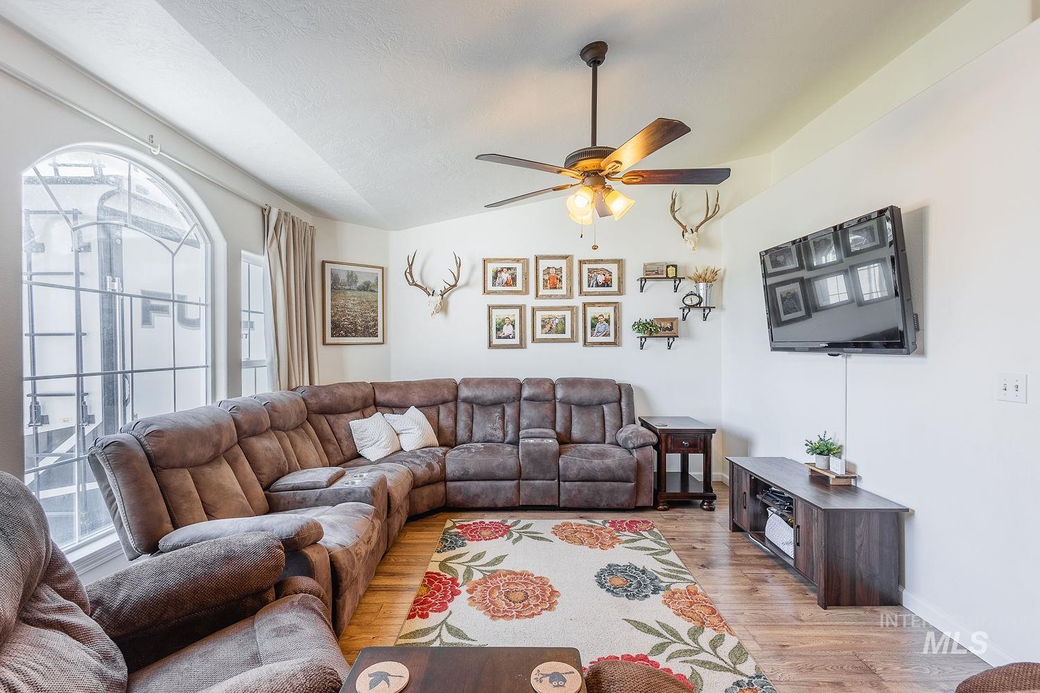 Living area featuring lofted ceiling, wood finished floors, and a ceiling fan