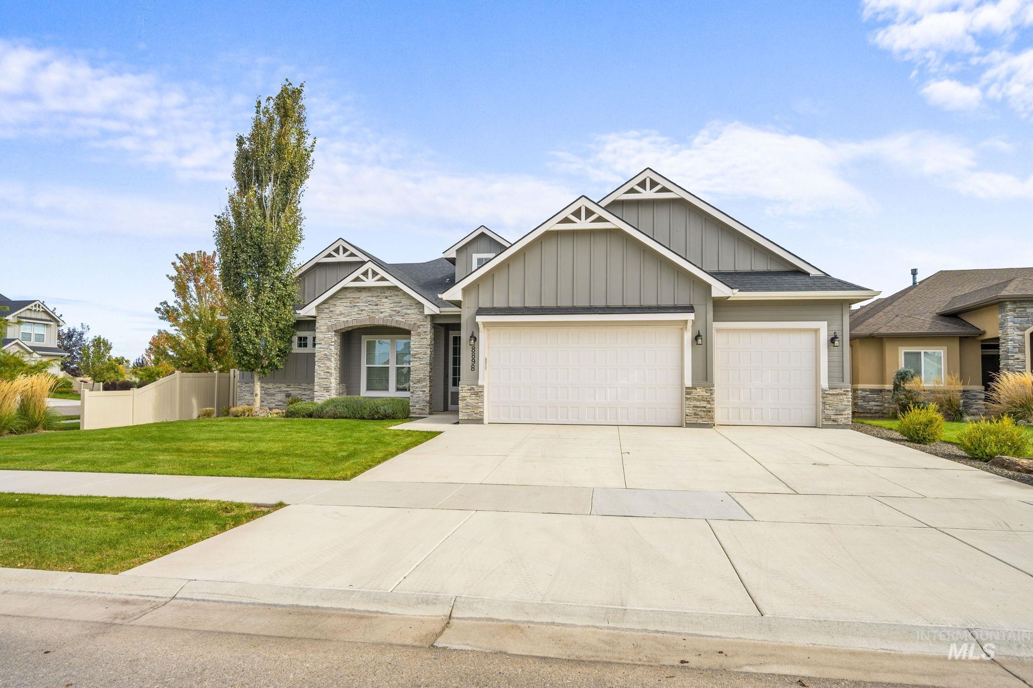 Craftsman house featuring board and batten siding, stone siding, driveway, and a garage