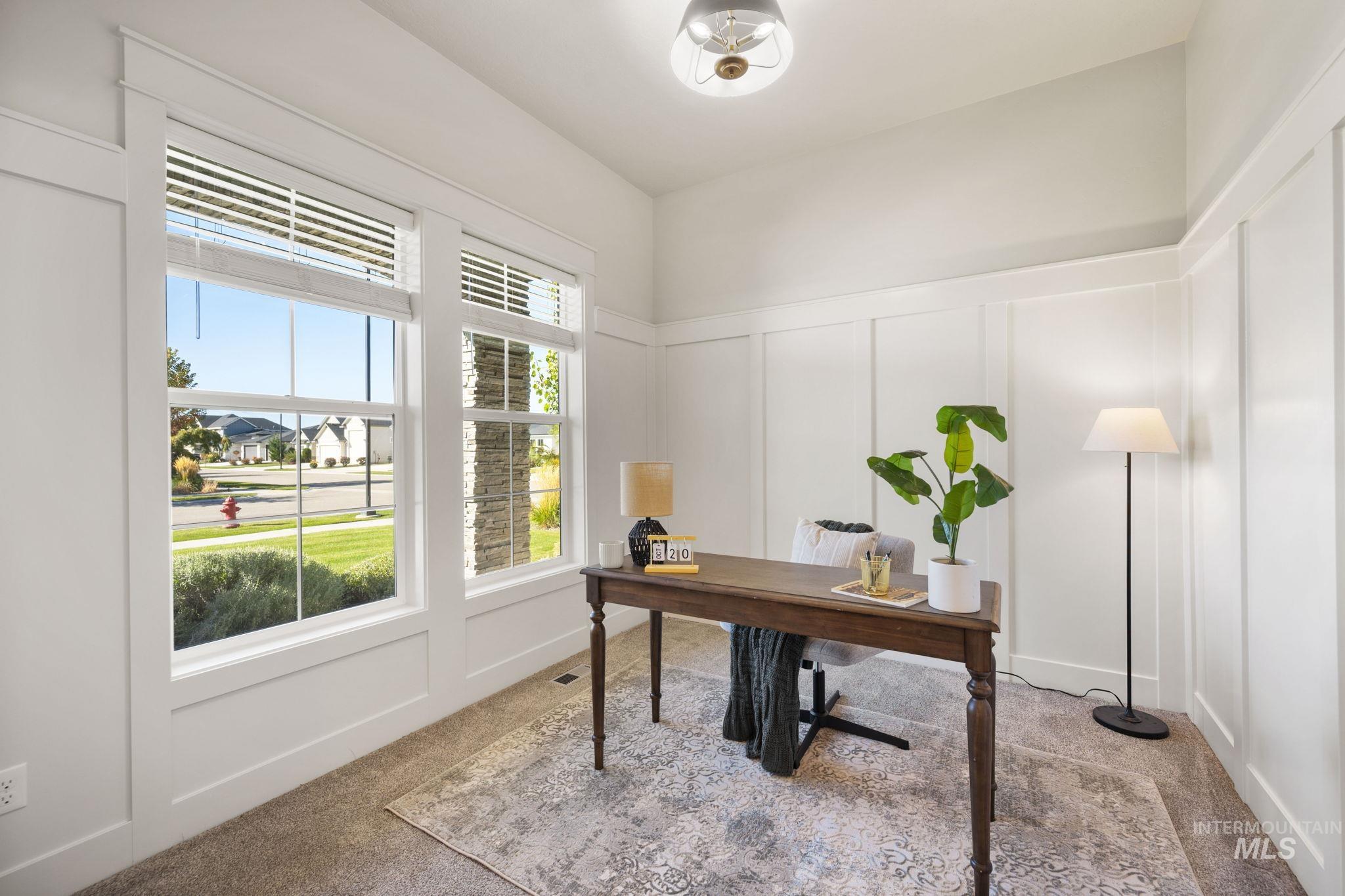 Home office with a decorative wall, light carpet, and wainscoting