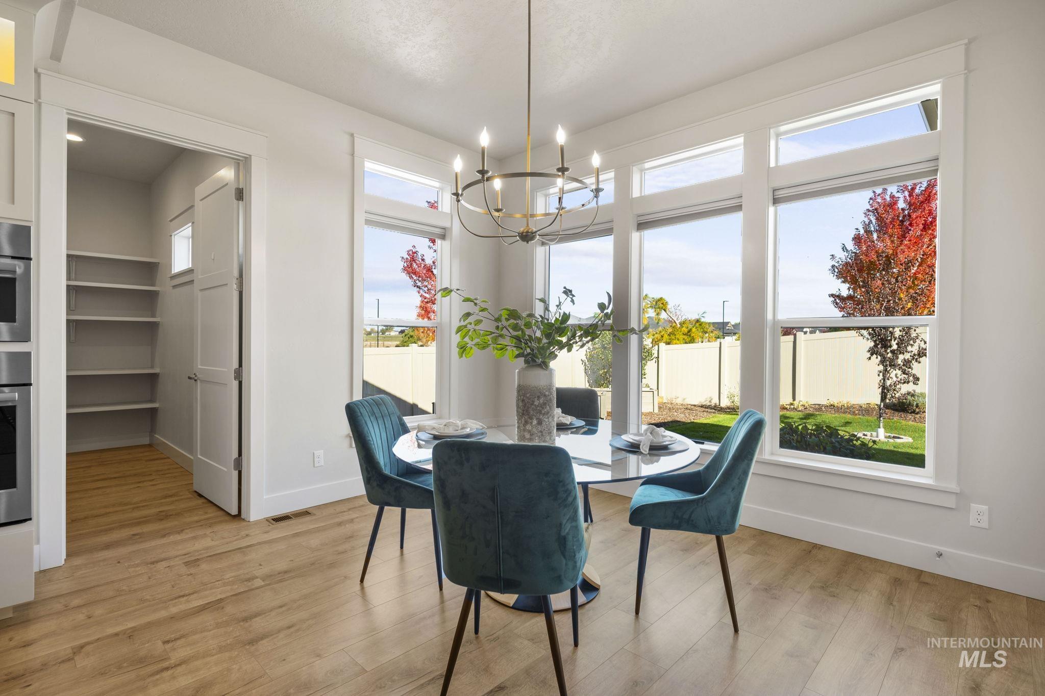 Dining space with plenty of natural light, light wood-style floors, and a chandelier