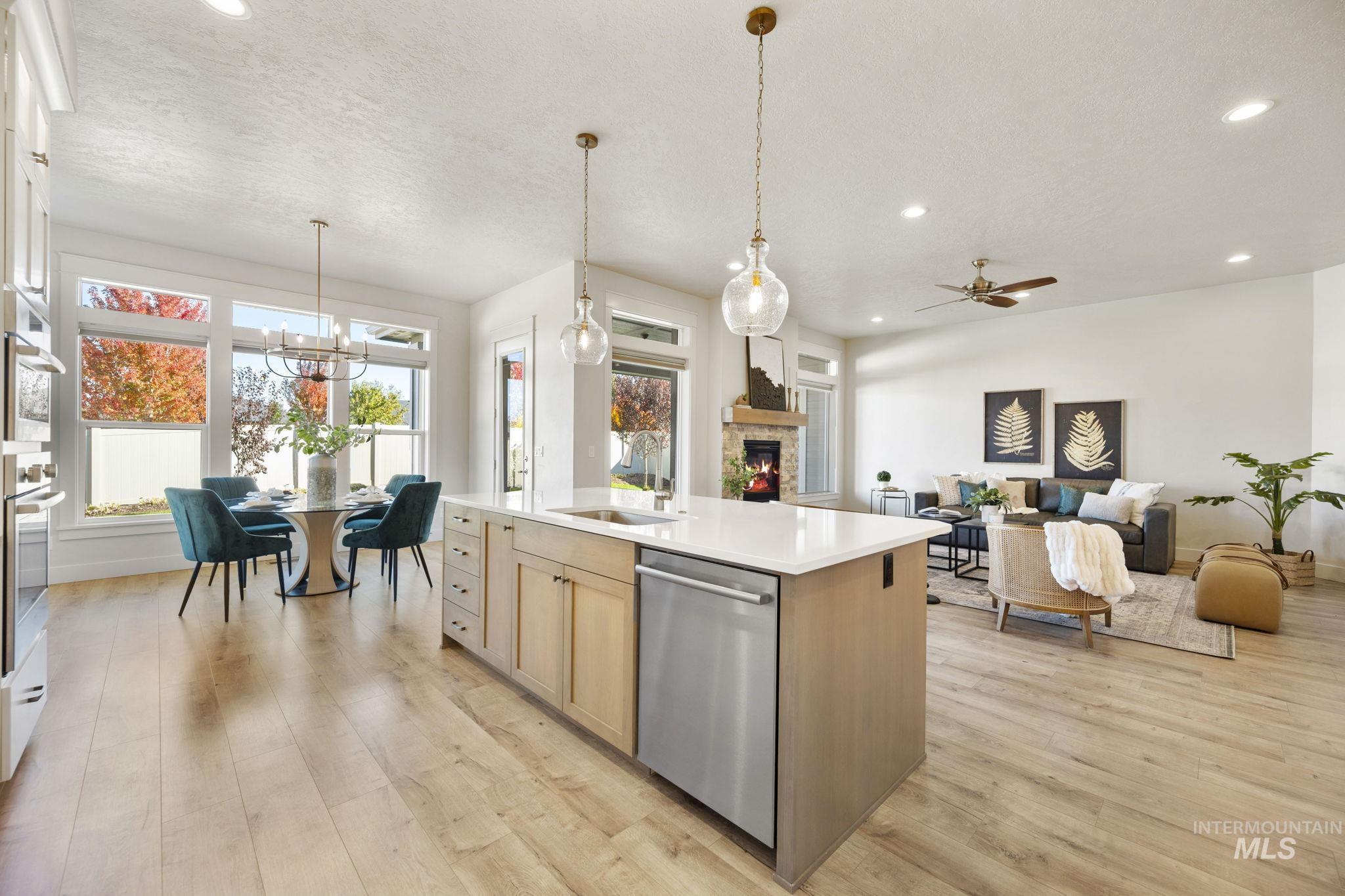 Kitchen featuring decorative light fixtures, open floor plan, a stone fireplace, stainless steel appliances, and recessed lighting