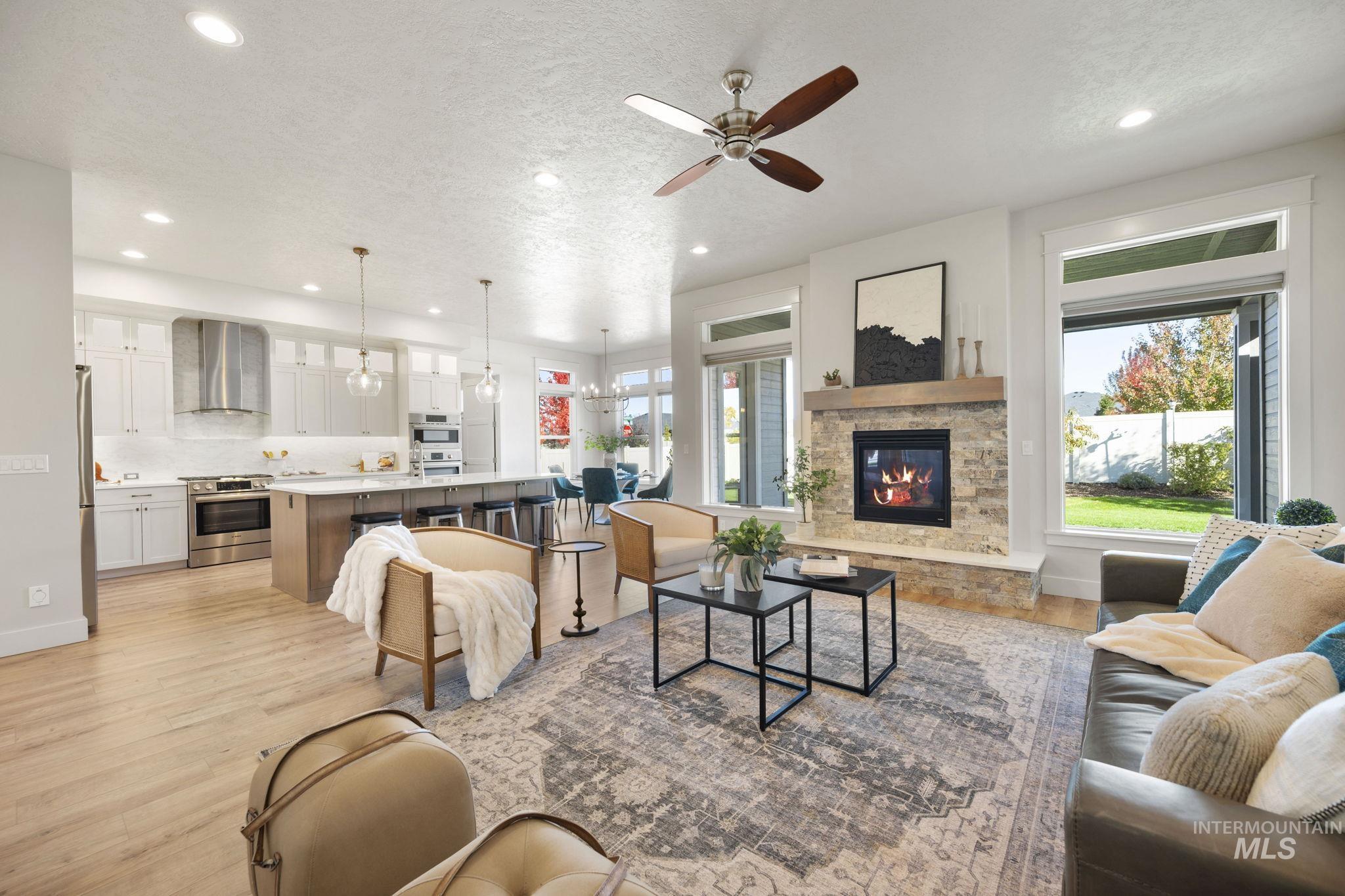 Living area featuring light wood-style flooring, a ceiling fan, recessed lighting, a textured ceiling, and a fireplace