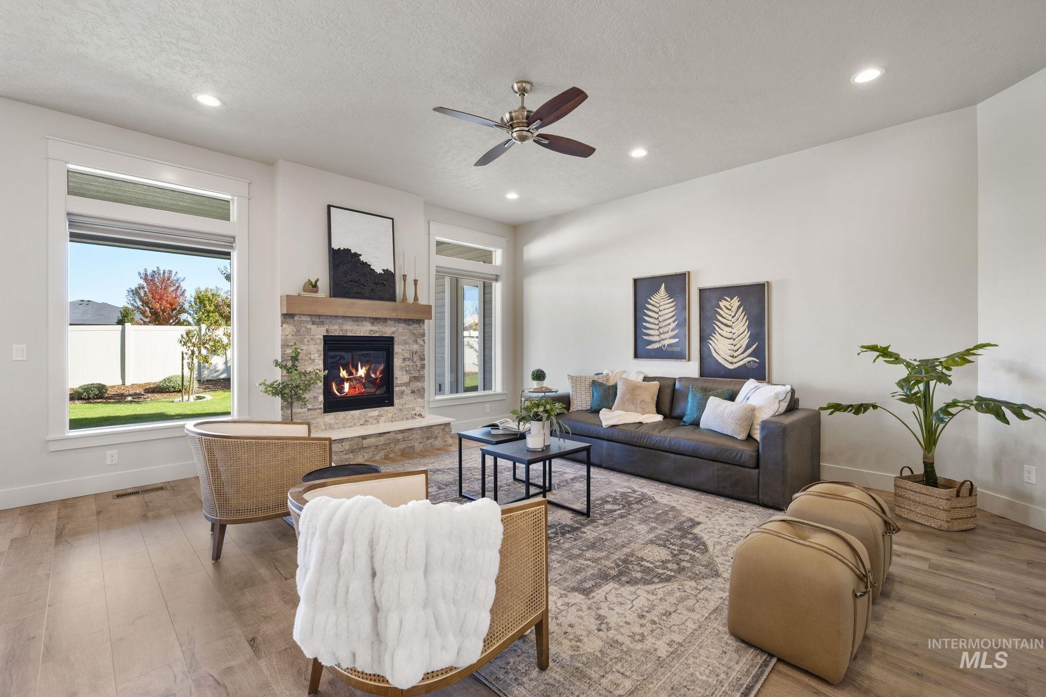 Living area featuring healthy amount of natural light, wood finished floors, recessed lighting, a stone fireplace, and a ceiling fan