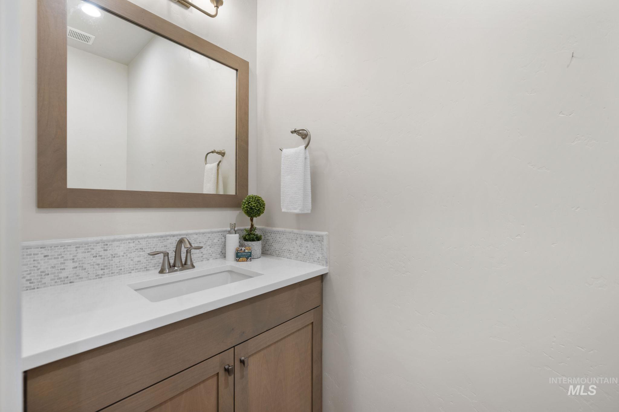 Bathroom featuring vanity and decorative backsplash