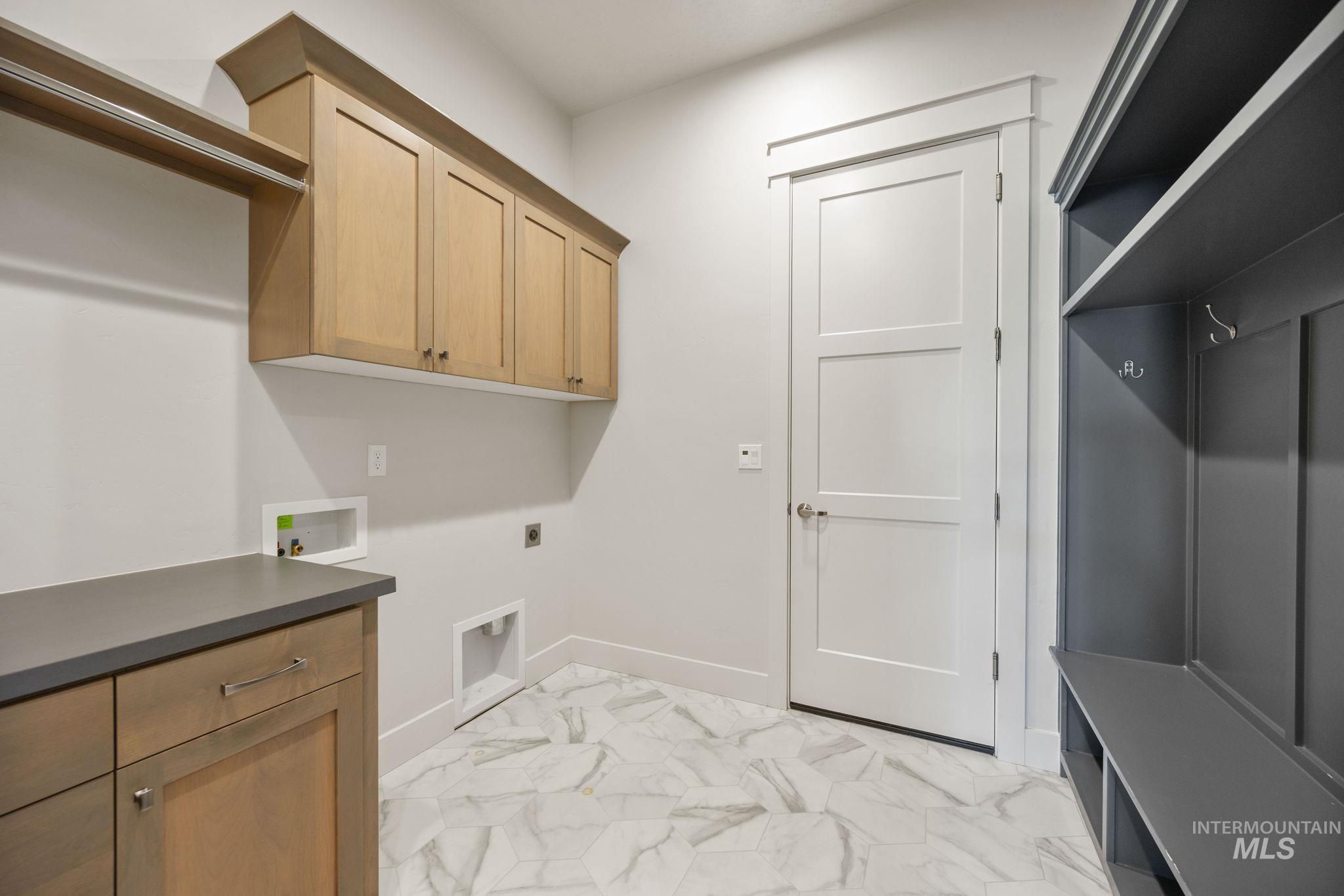 Laundry area with light marble finish flooring, cabinet space, electric dryer hookup, and hookup for a washing machine