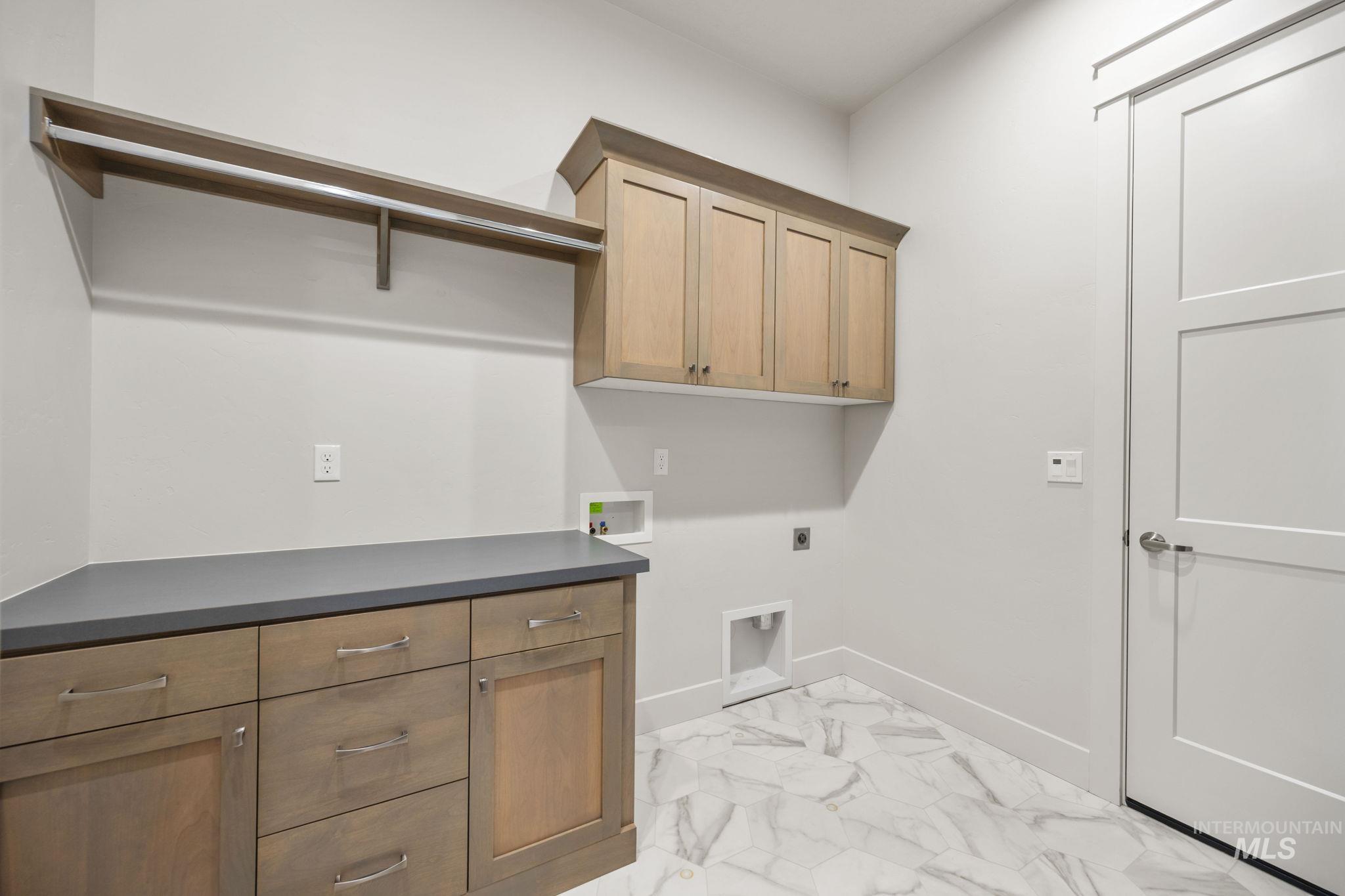 Laundry area featuring light marble finish flooring, hookup for an electric dryer, cabinet space, and washer hookup