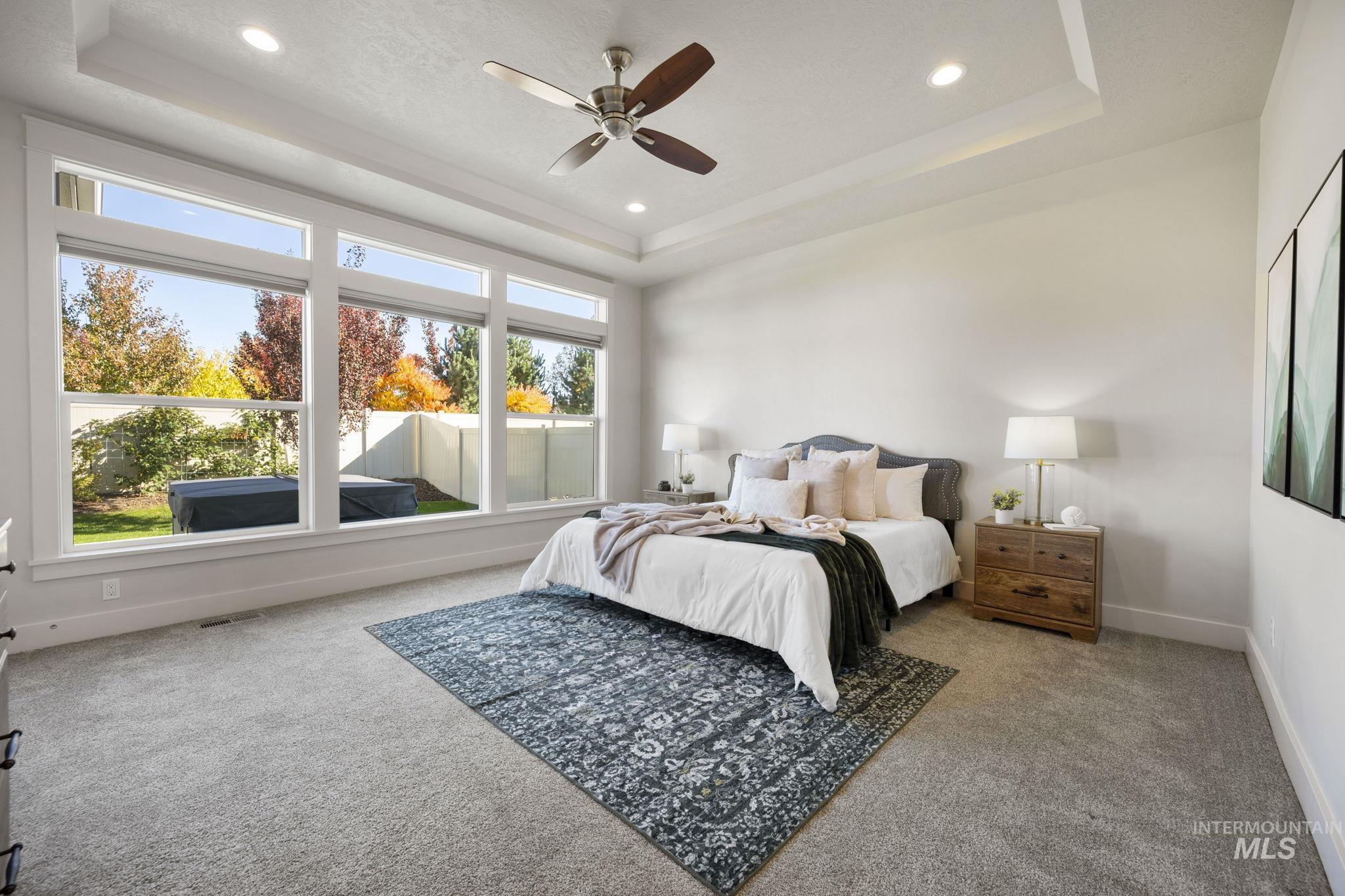 Bedroom featuring a raised ceiling, light colored carpet, a ceiling fan, and recessed lighting