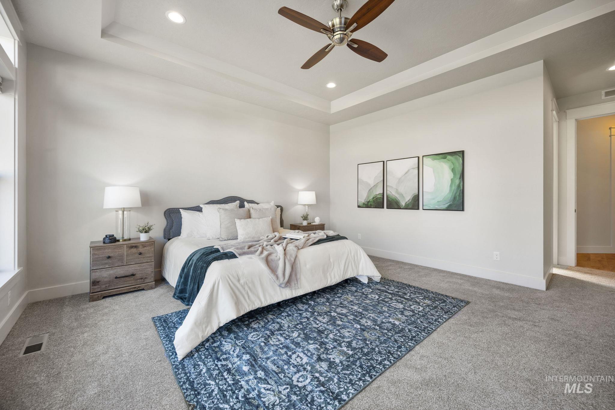 Bedroom featuring a tray ceiling, light carpet, recessed lighting, and ceiling fan
