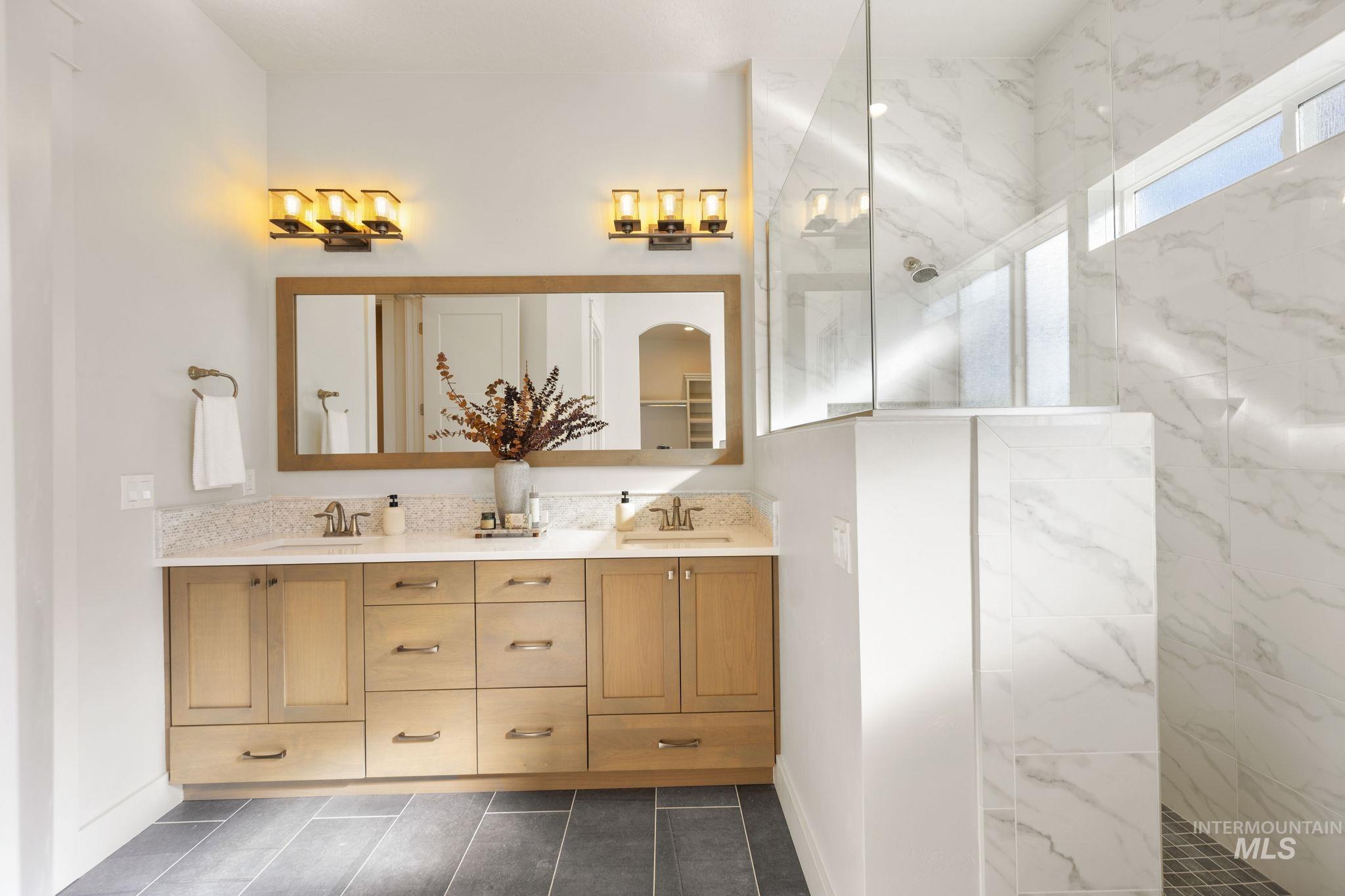 Full bathroom featuring a marble finish shower and double vanity