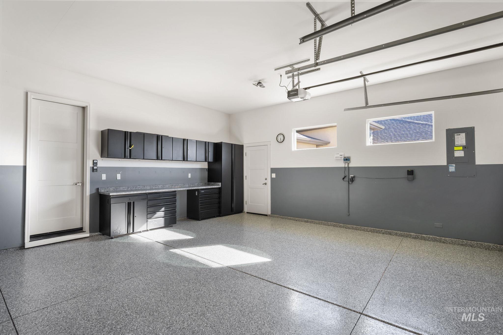 Kitchen featuring light countertops, dark cabinets, electric panel, and dark speckled floor