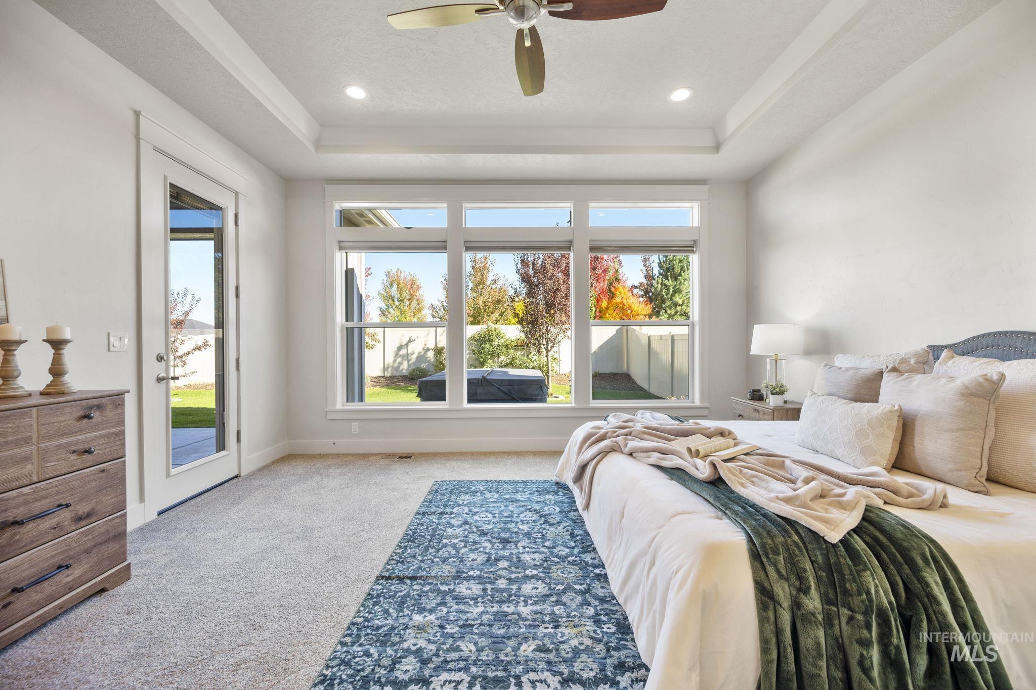 Bedroom with light carpet, a tray ceiling, access to exterior, a ceiling fan, and recessed lighting