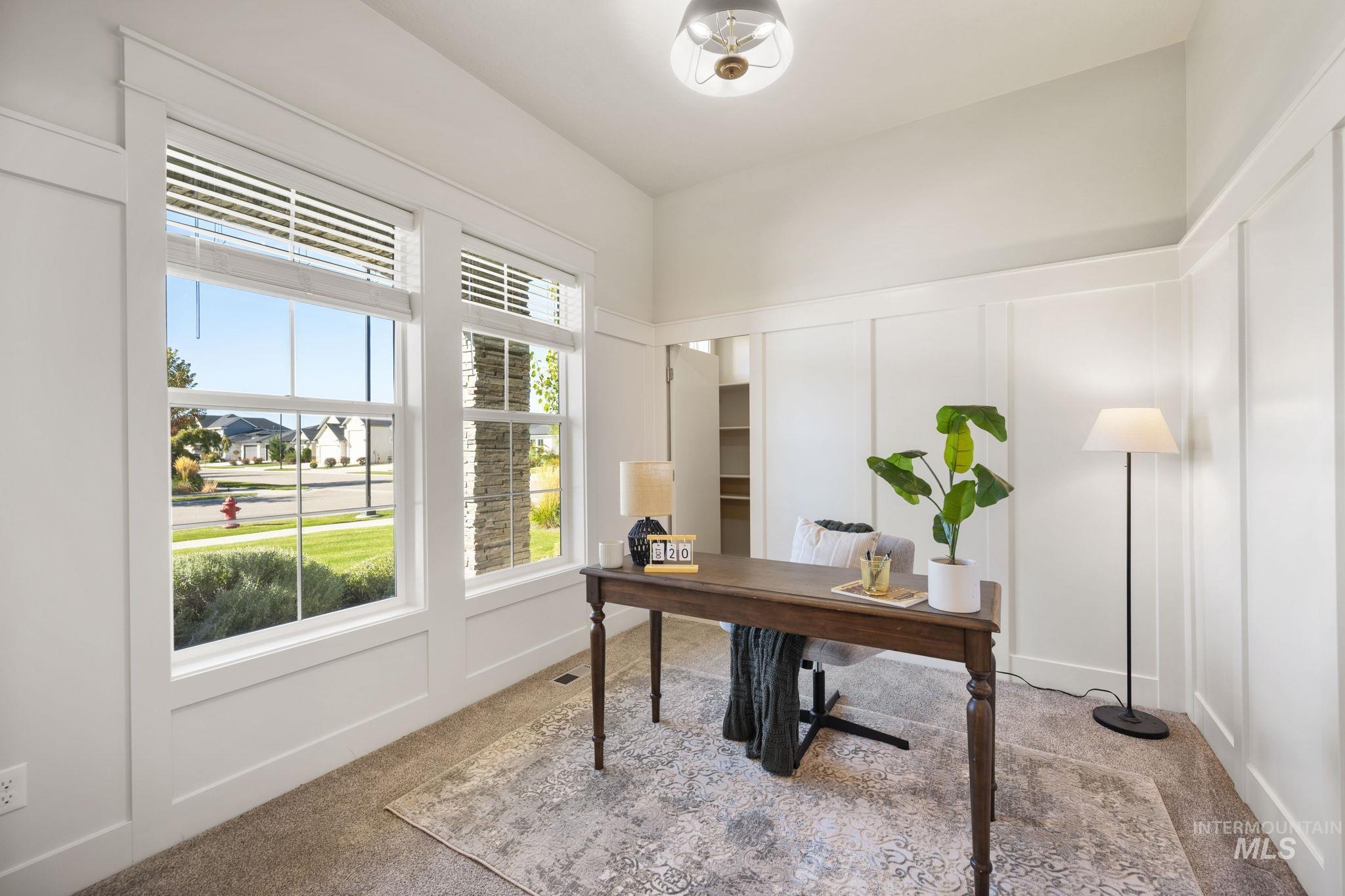Office space featuring a decorative wall, light carpet, and a wainscoted wall