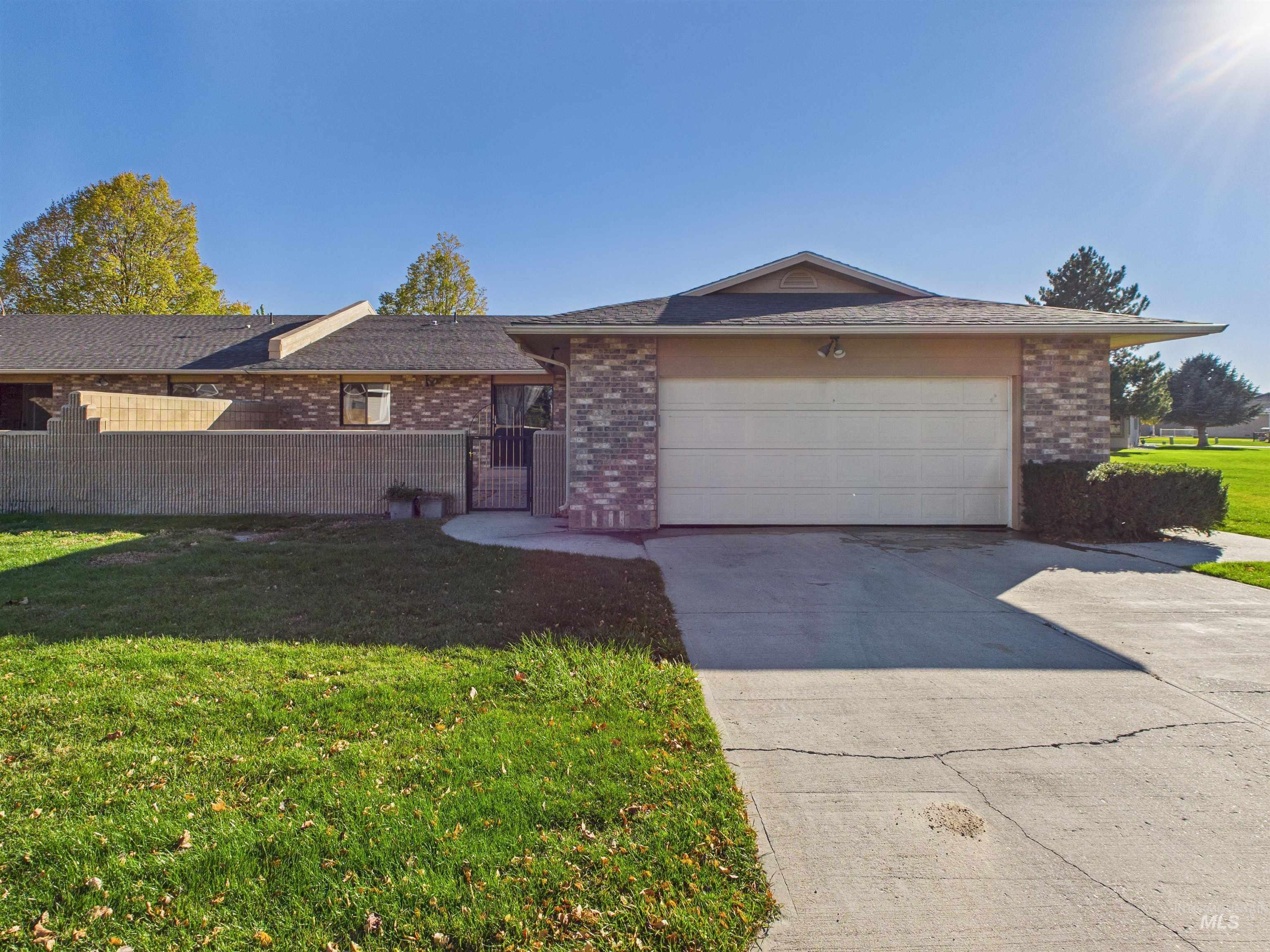 Single story home featuring brick siding, driveway, a garage, and a gate