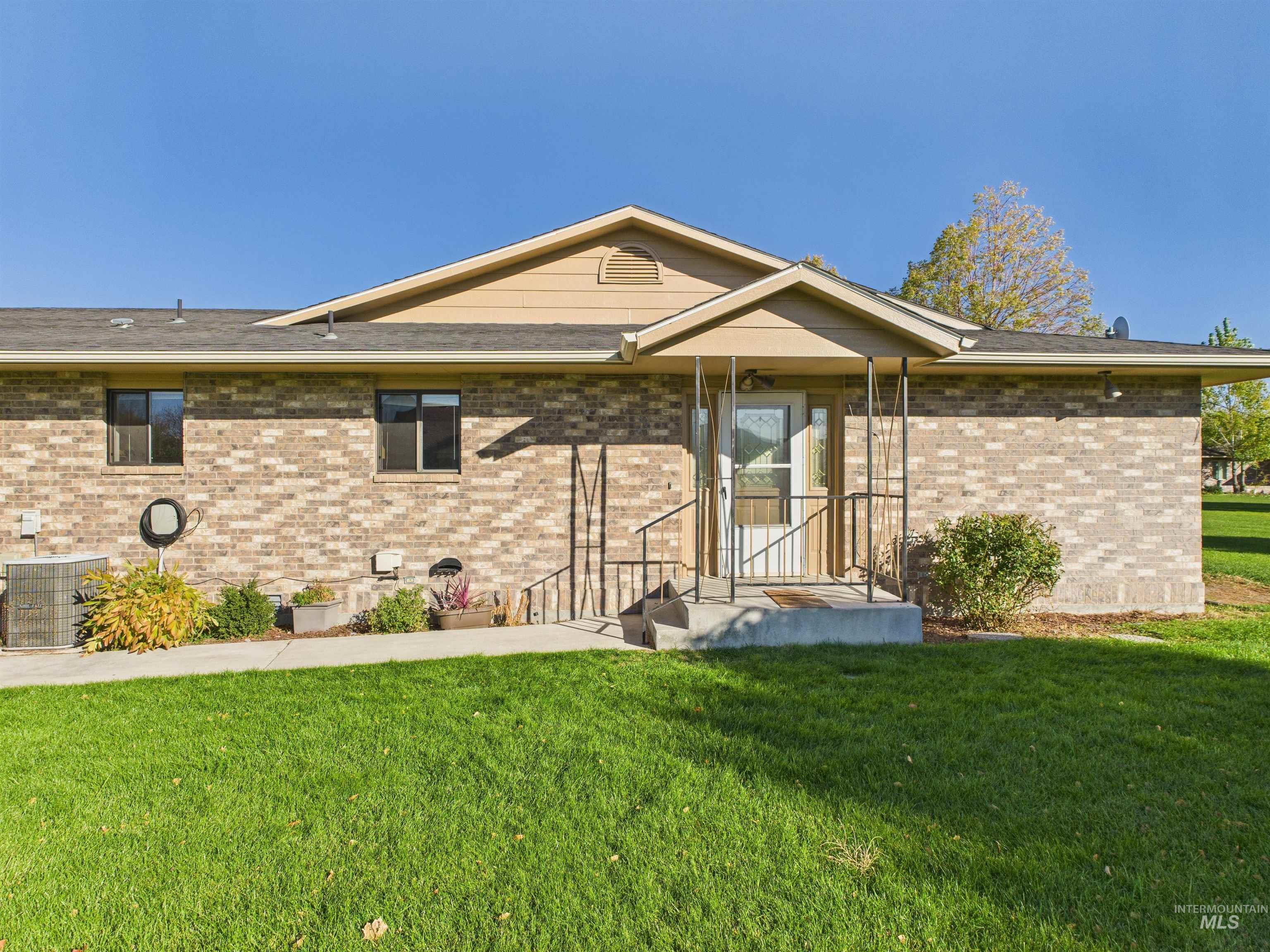 Rear view of property featuring a lawn and brick siding