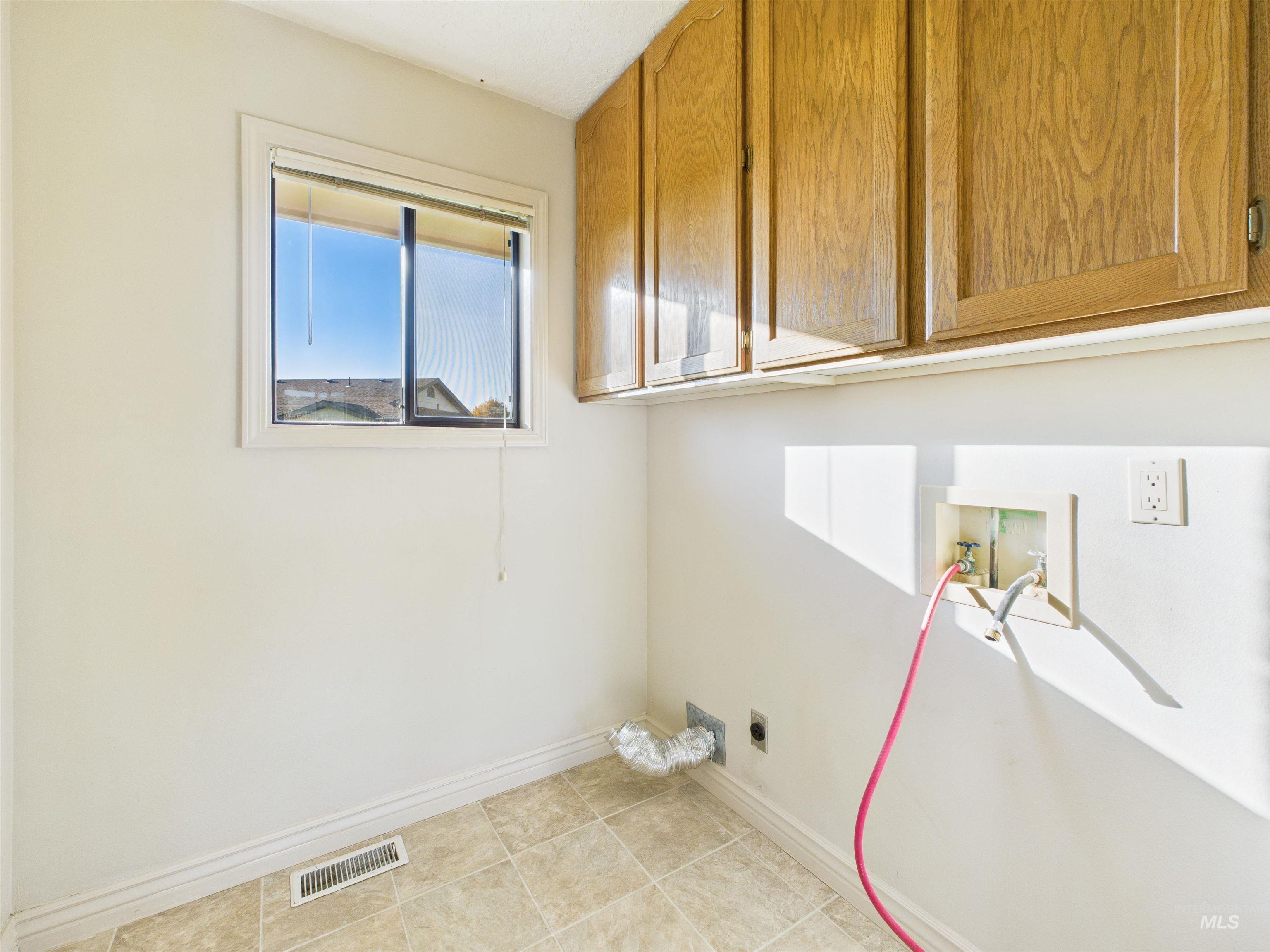 Laundry area featuring washer hookup, cabinet space, light tile patterned floors, and hookup for an electric dryer