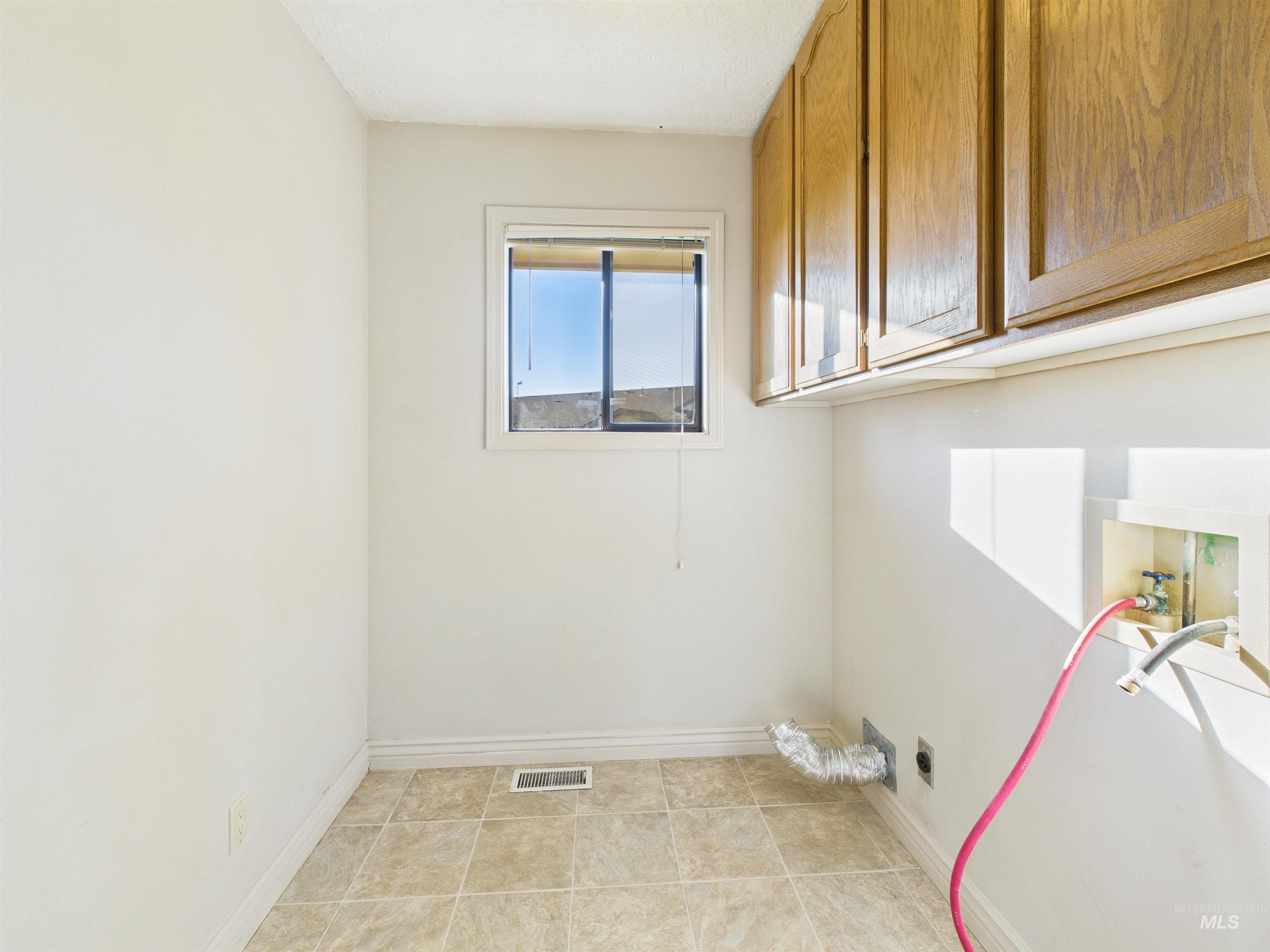 Washroom featuring hookup for a washing machine, cabinet space, light tile patterned flooring, and hookup for an electric dryer