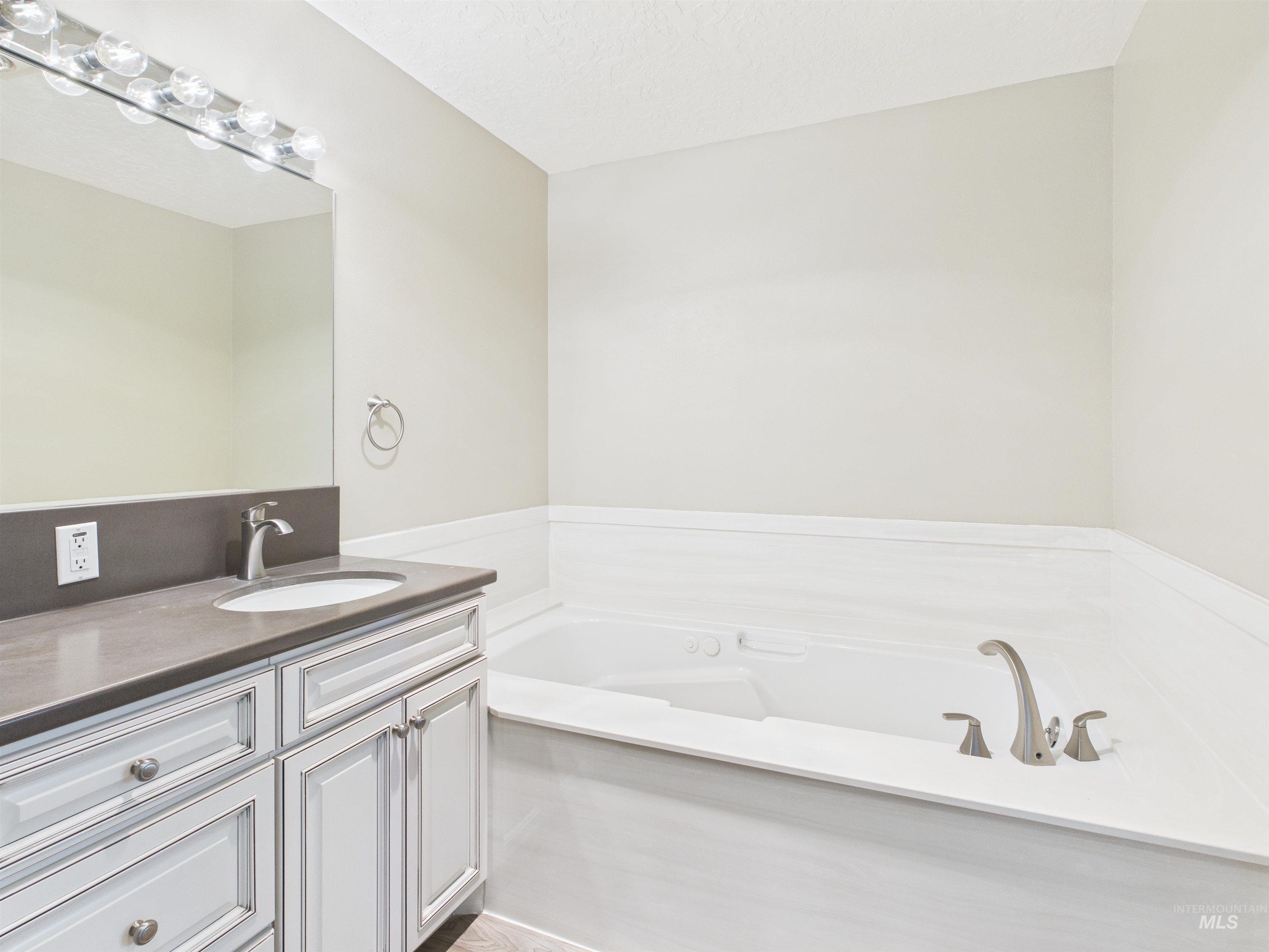 Bathroom with vanity, a bath, and a textured ceiling