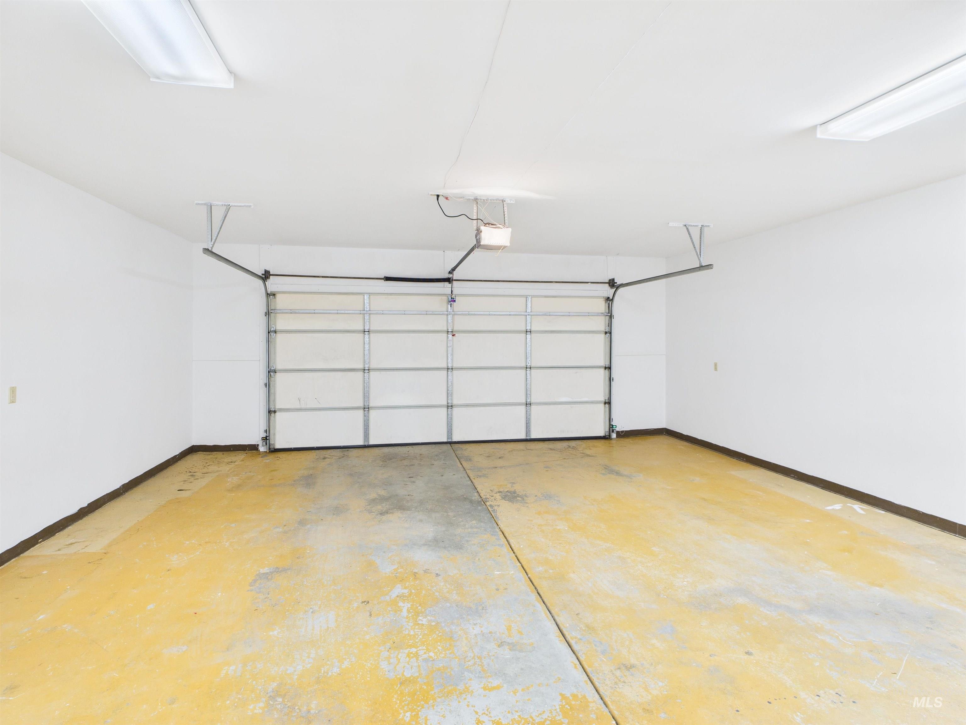 Garage featuring baseboards and a garage door opener