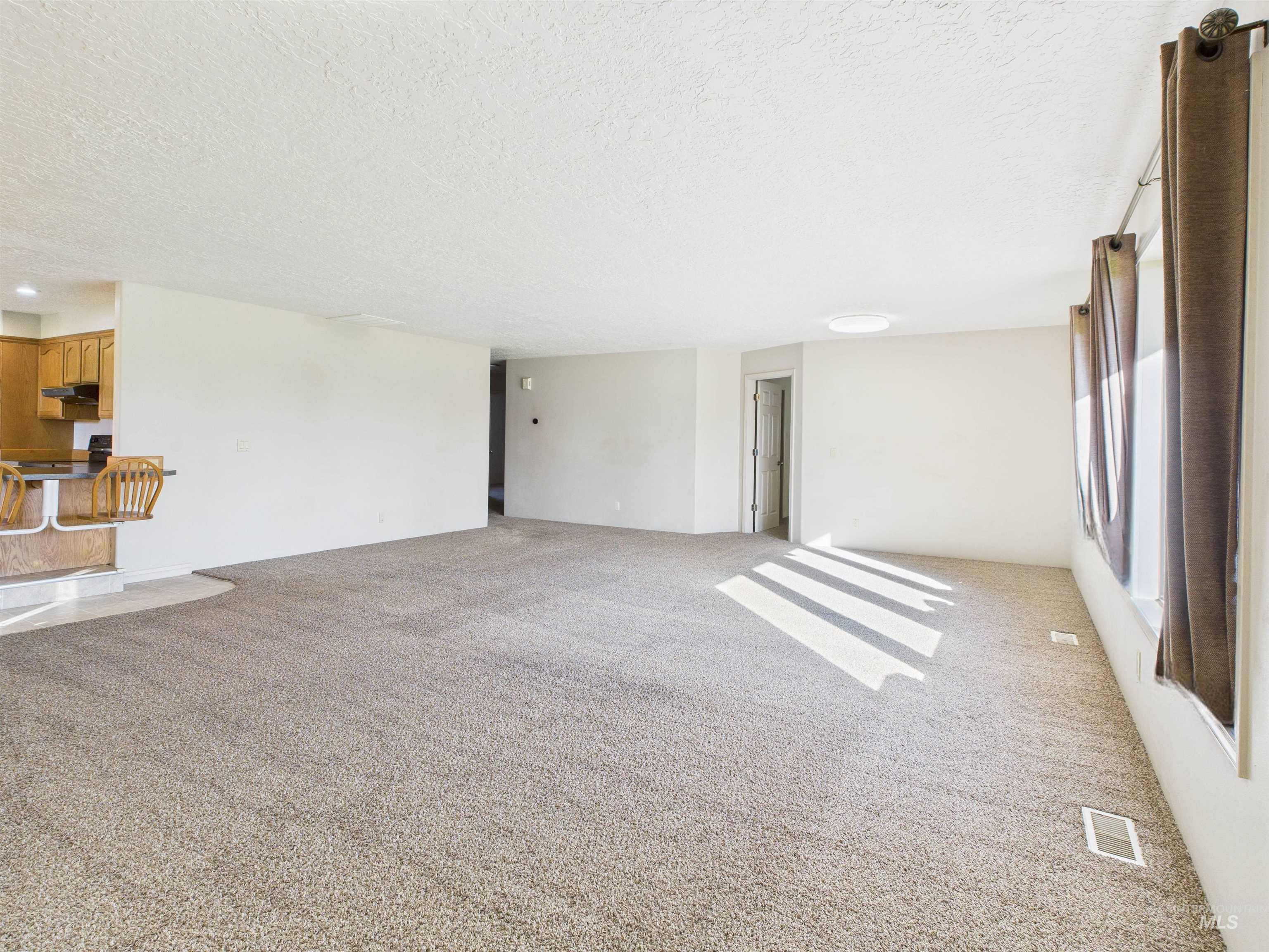 Unfurnished living room with light colored carpet and a textured ceiling