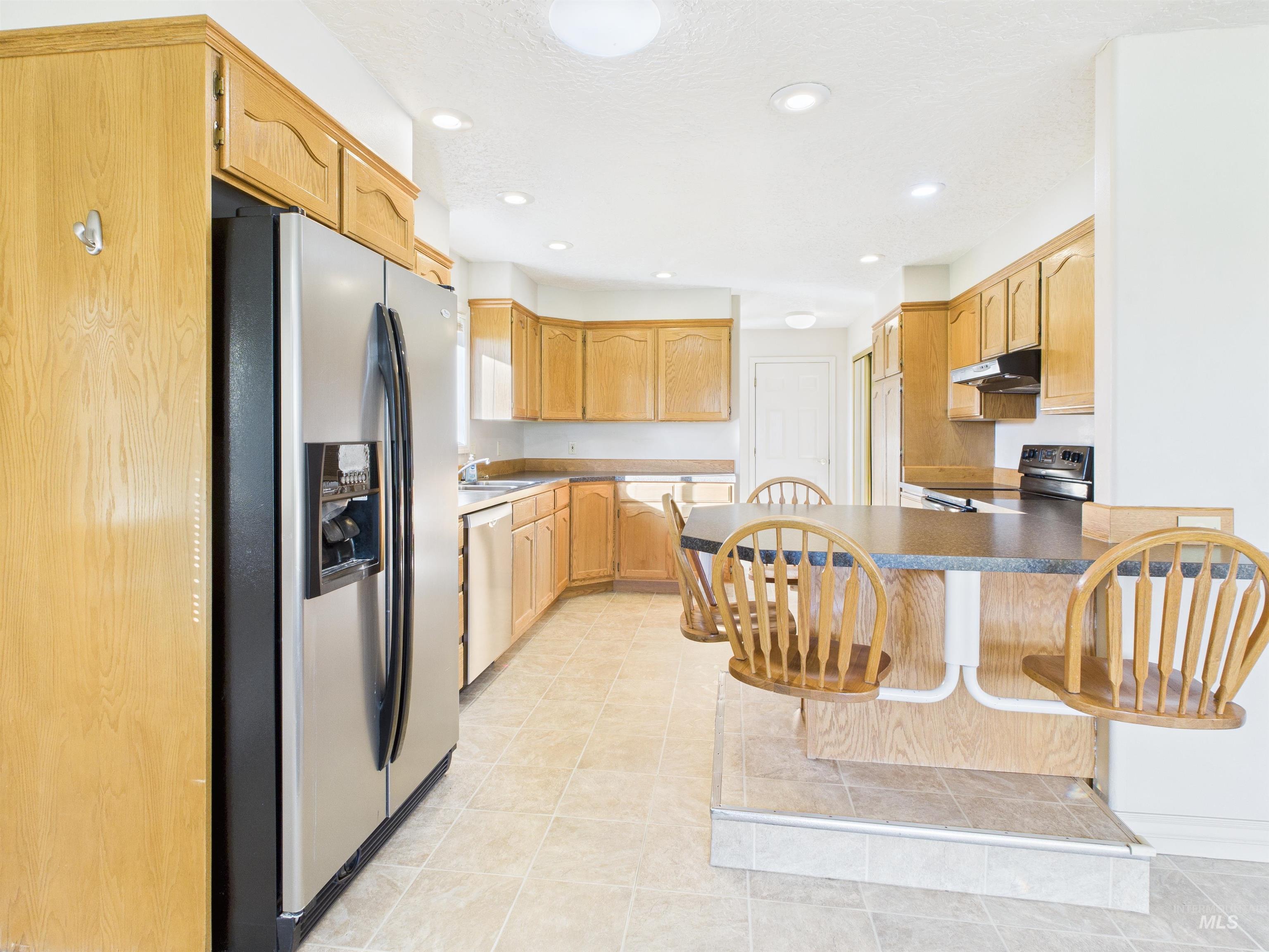 Kitchen with appliances with stainless steel finishes, a peninsula, recessed lighting, a breakfast bar area, and light tile patterned flooring