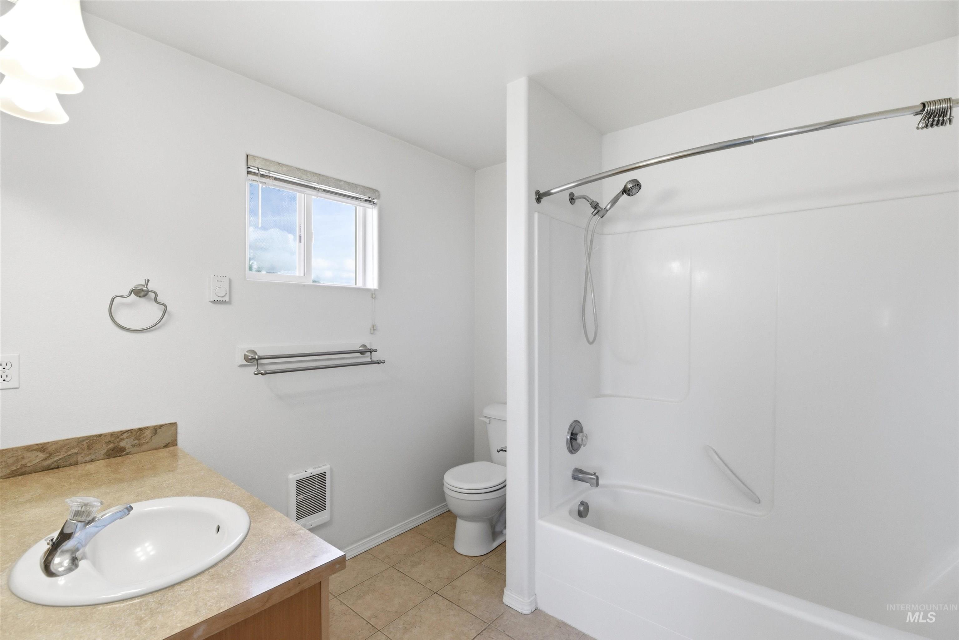 Bathroom with vanity, light tile patterned floors, shower / tub combination, and heating unit