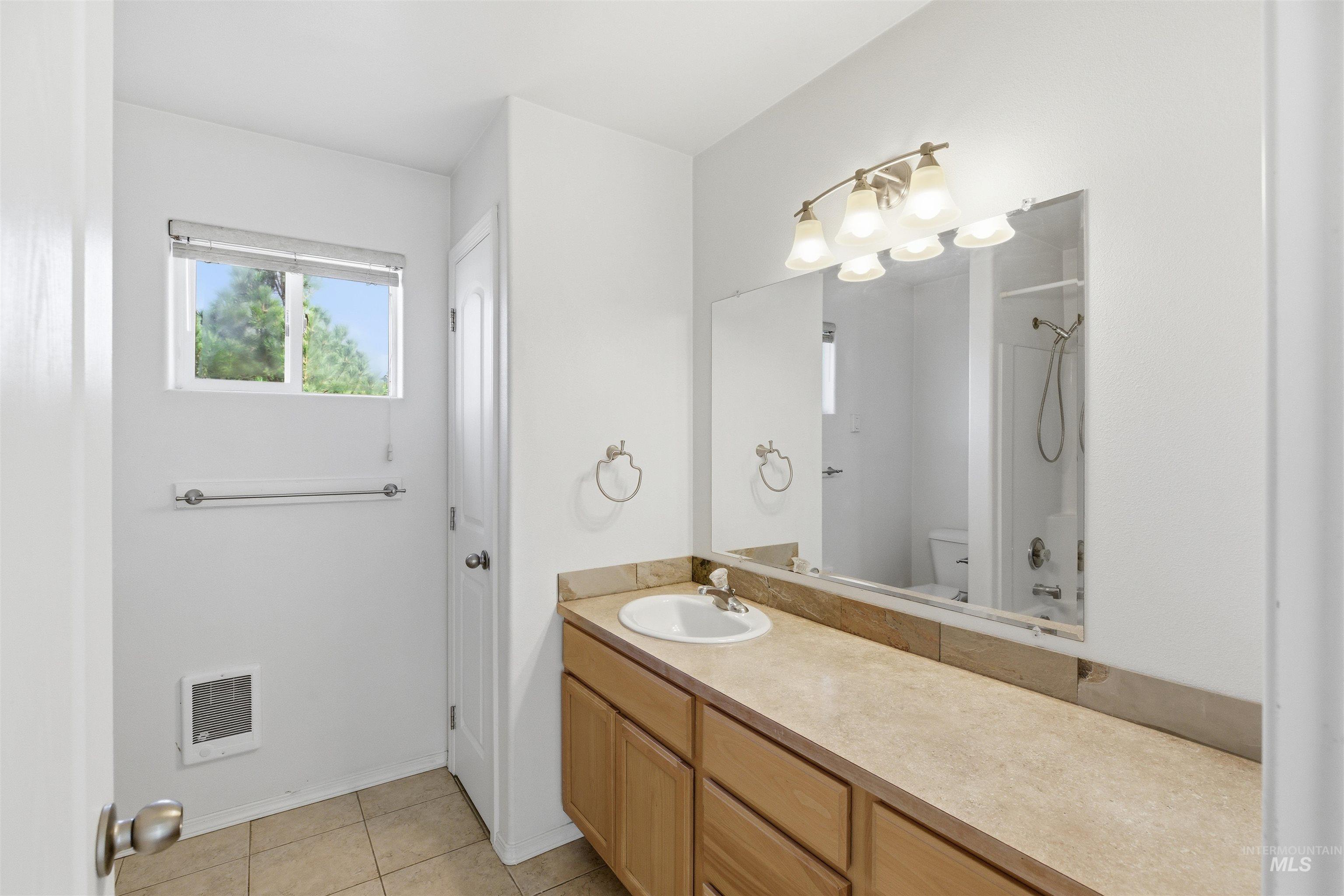 Bathroom featuring vanity, light tile patterned floors, shower / tub combination, and heating unit