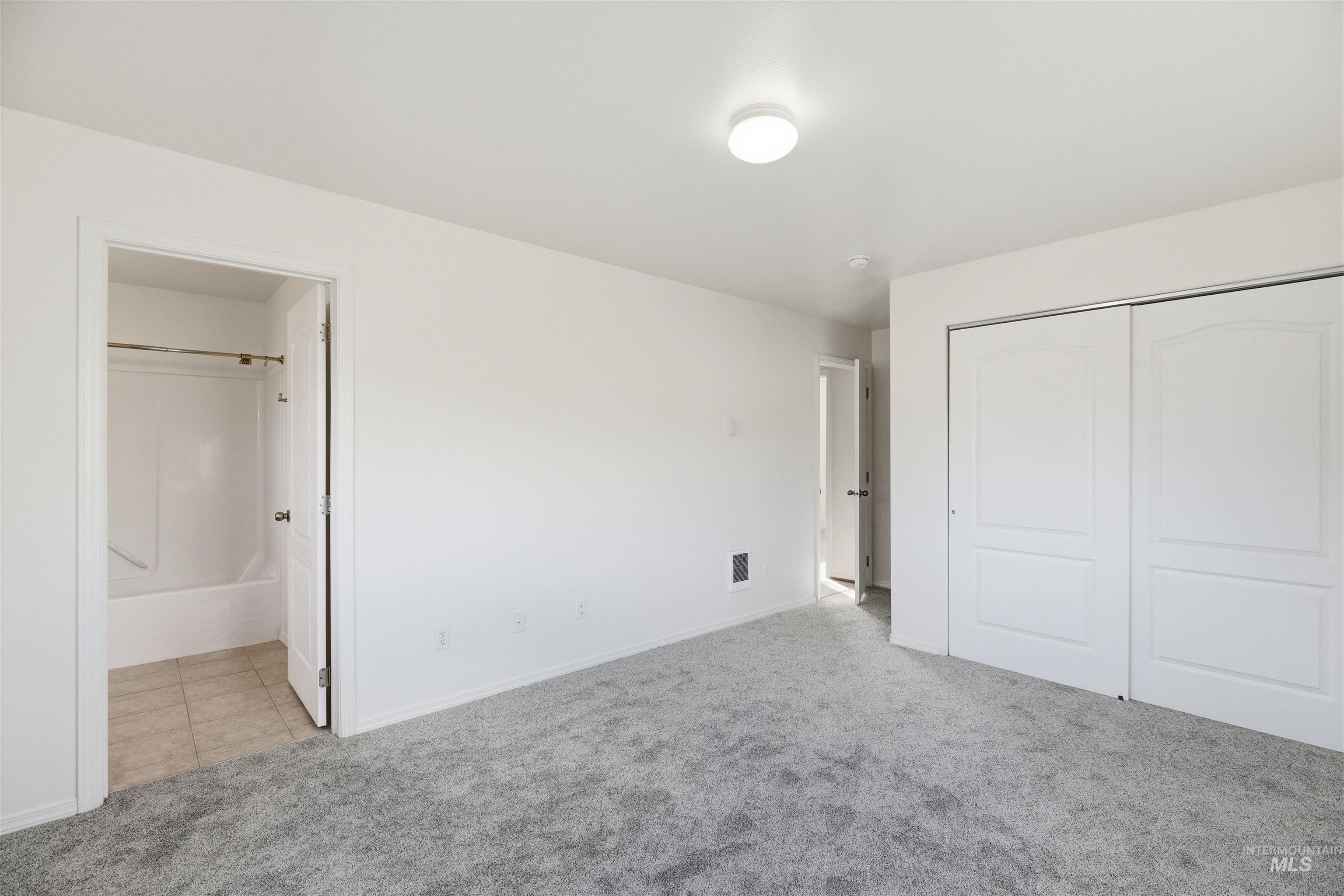 Unfurnished bedroom with light carpet, a closet, and ensuite bath