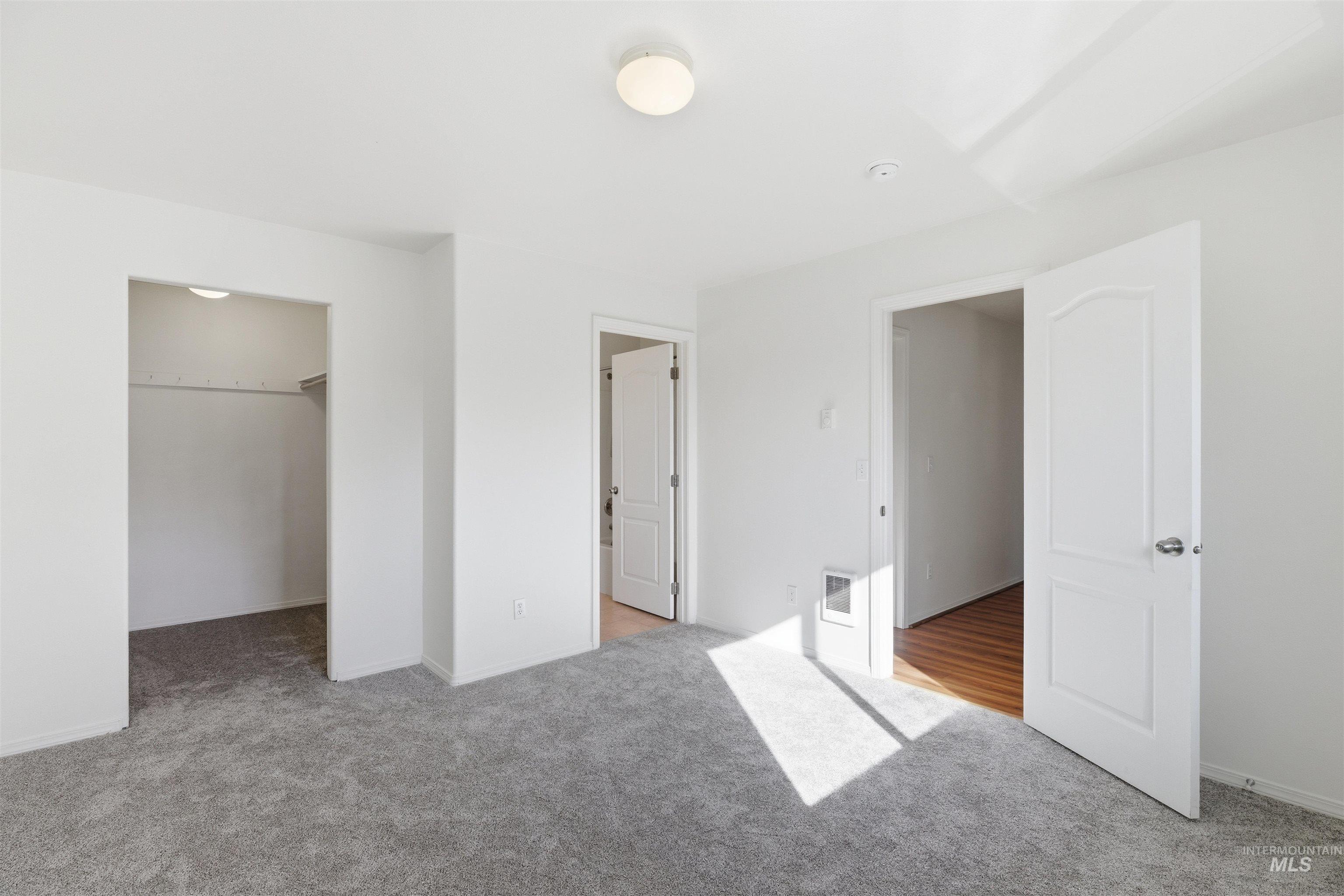 Unfurnished bedroom with a spacious closet and light carpet