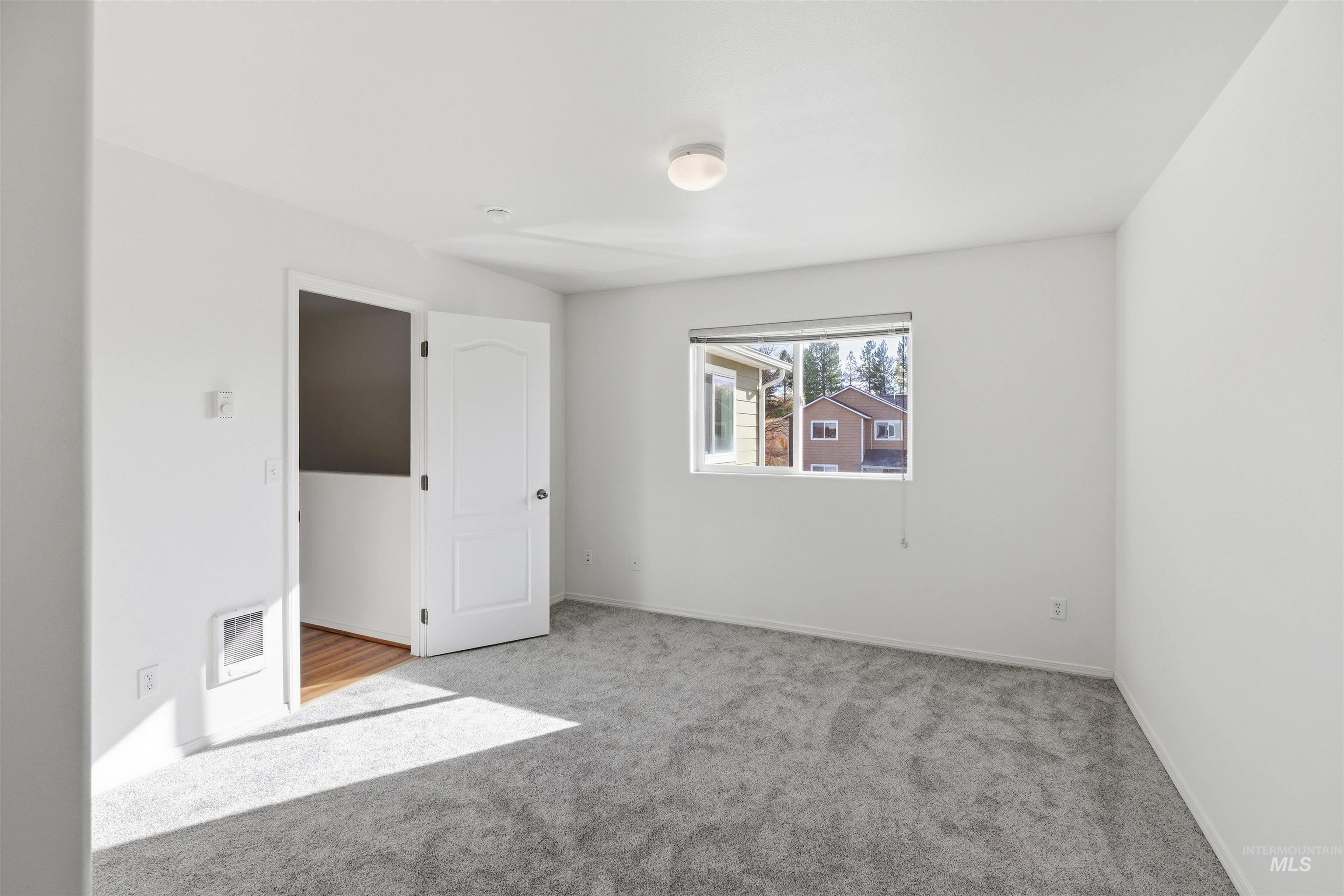 Unfurnished bedroom featuring carpet floors and heating unit