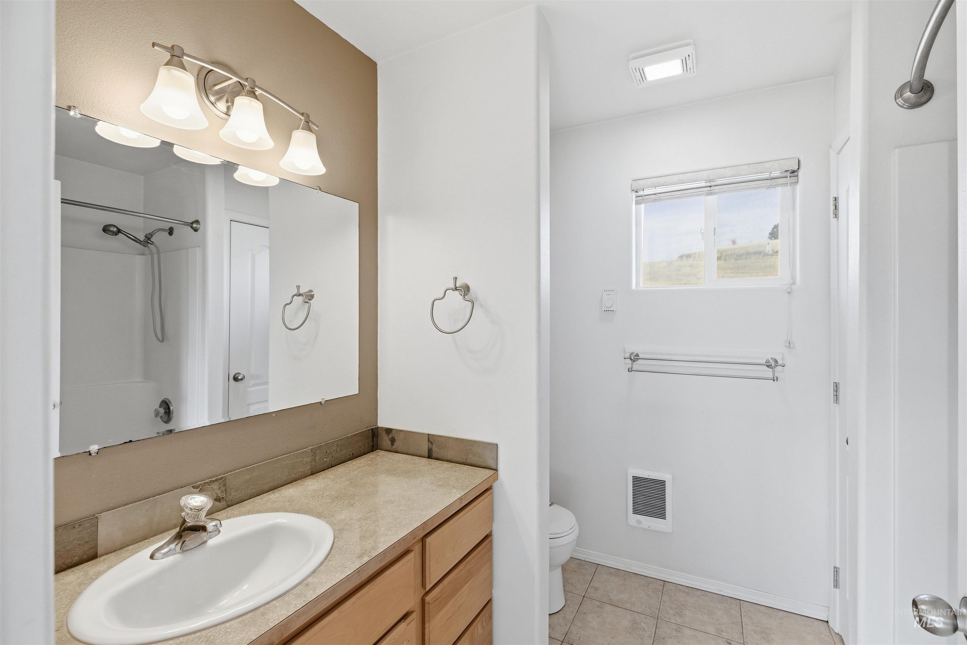 Bathroom featuring vanity, light tile patterned floors, and heating unit