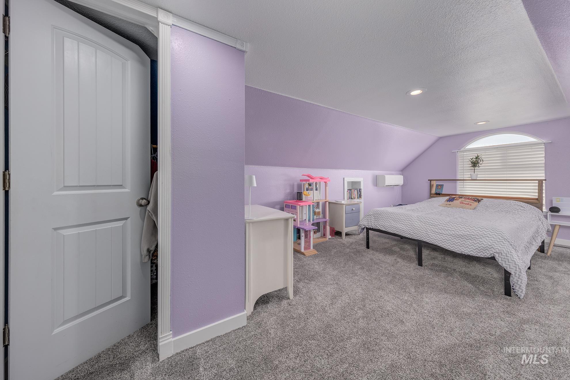 Bedroom with carpet, vaulted ceiling, and a textured ceiling