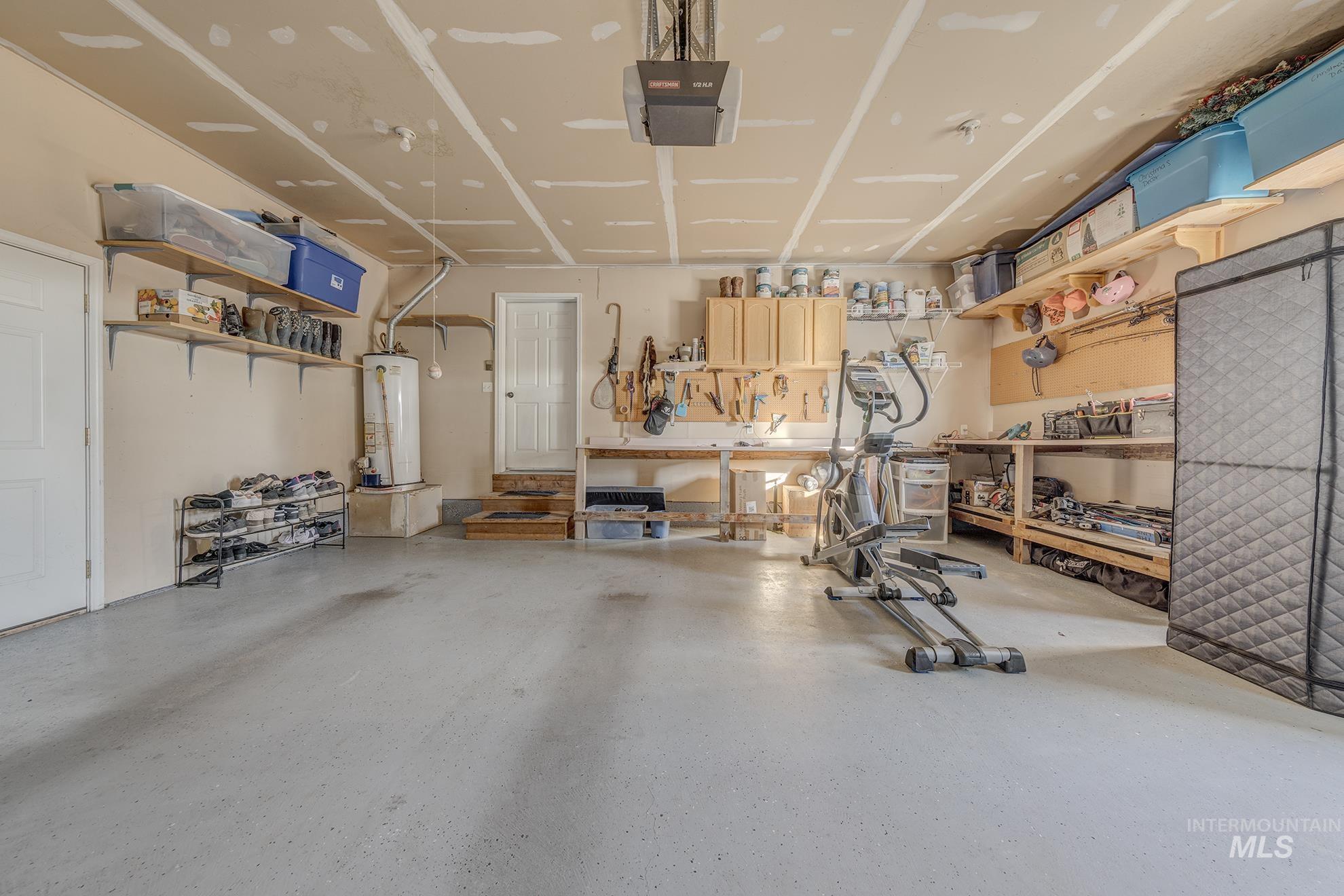 Garage featuring a workshop area, gas water heater, and a garage door opener
