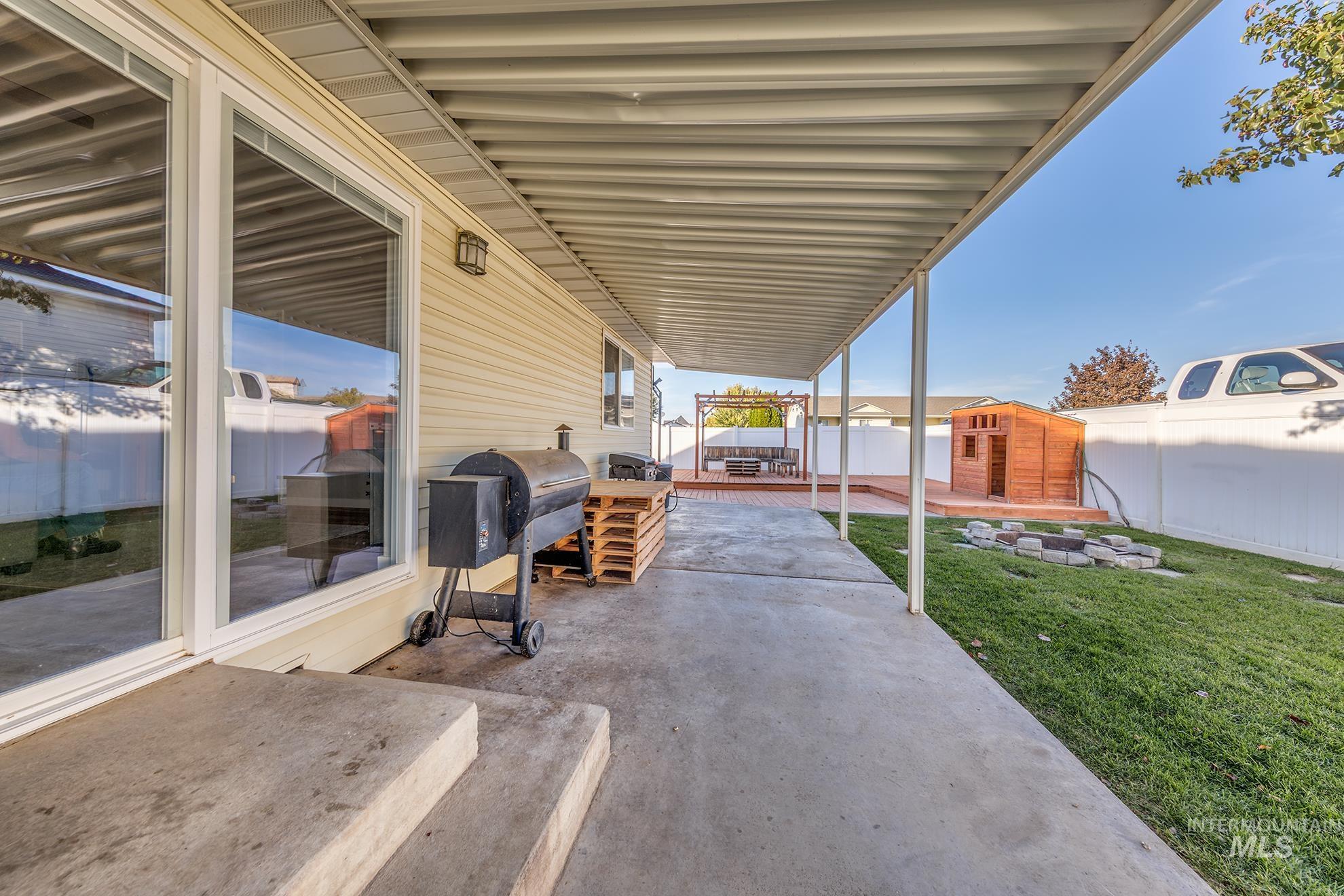 Fenced backyard featuring a shed, a patio, and area for grilling