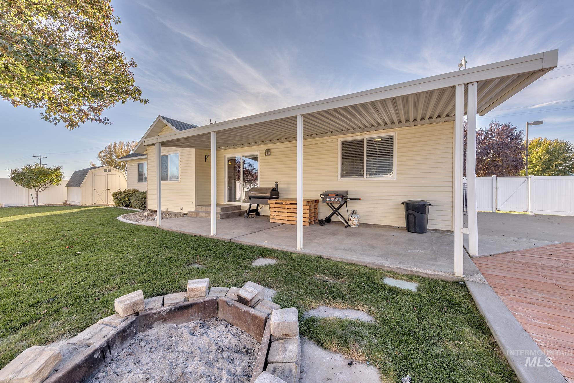 Back of house with a shed, a patio, and an outdoor fire pit