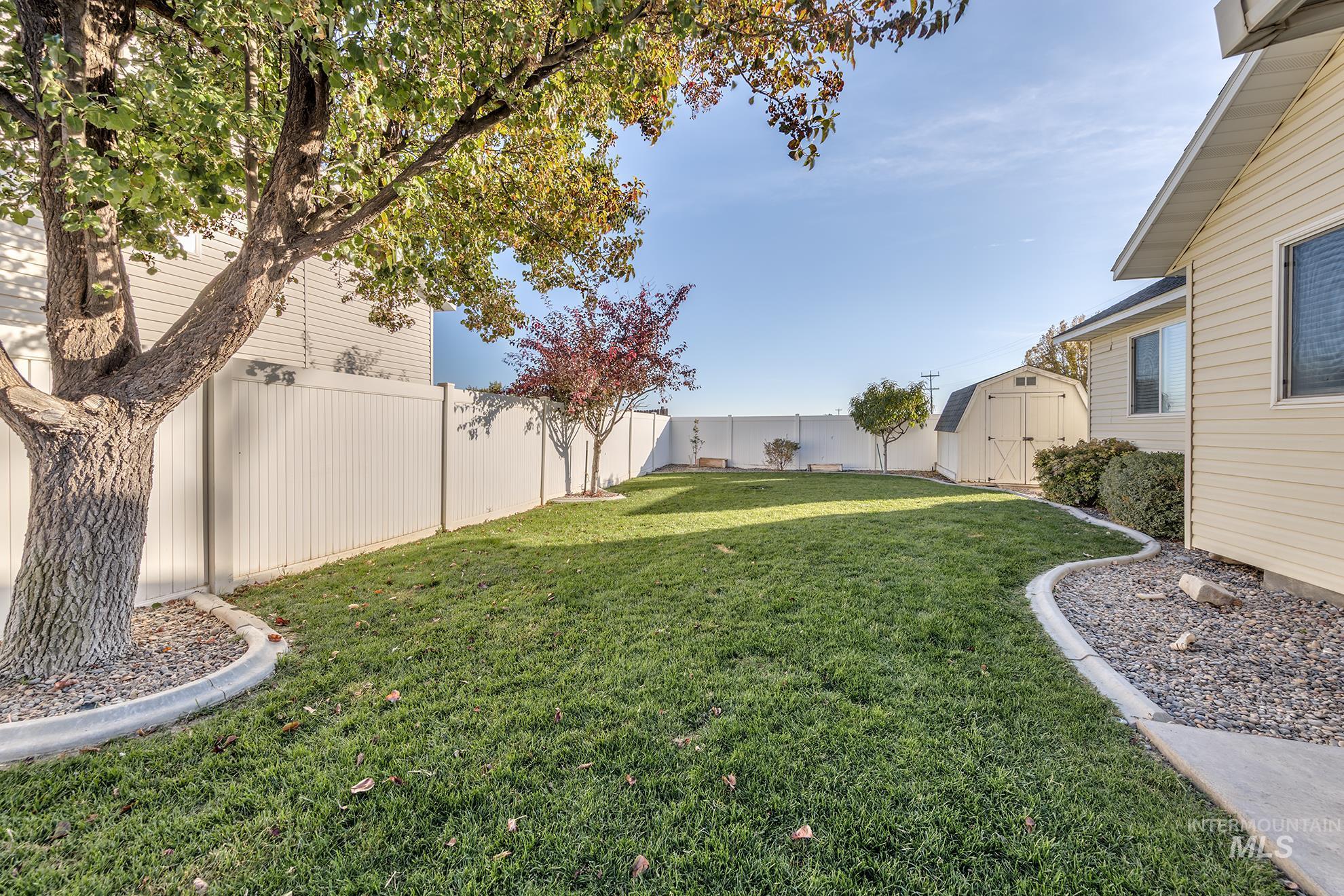 Fenced backyard featuring a storage shed