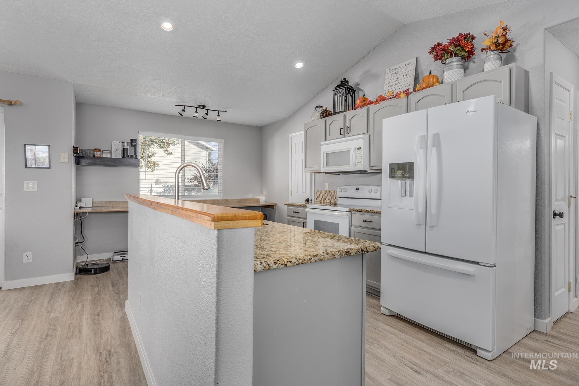Kitchen featuring white appliances, light wood-style floors, gray cabinetry, lofted ceiling, and recessed lighting