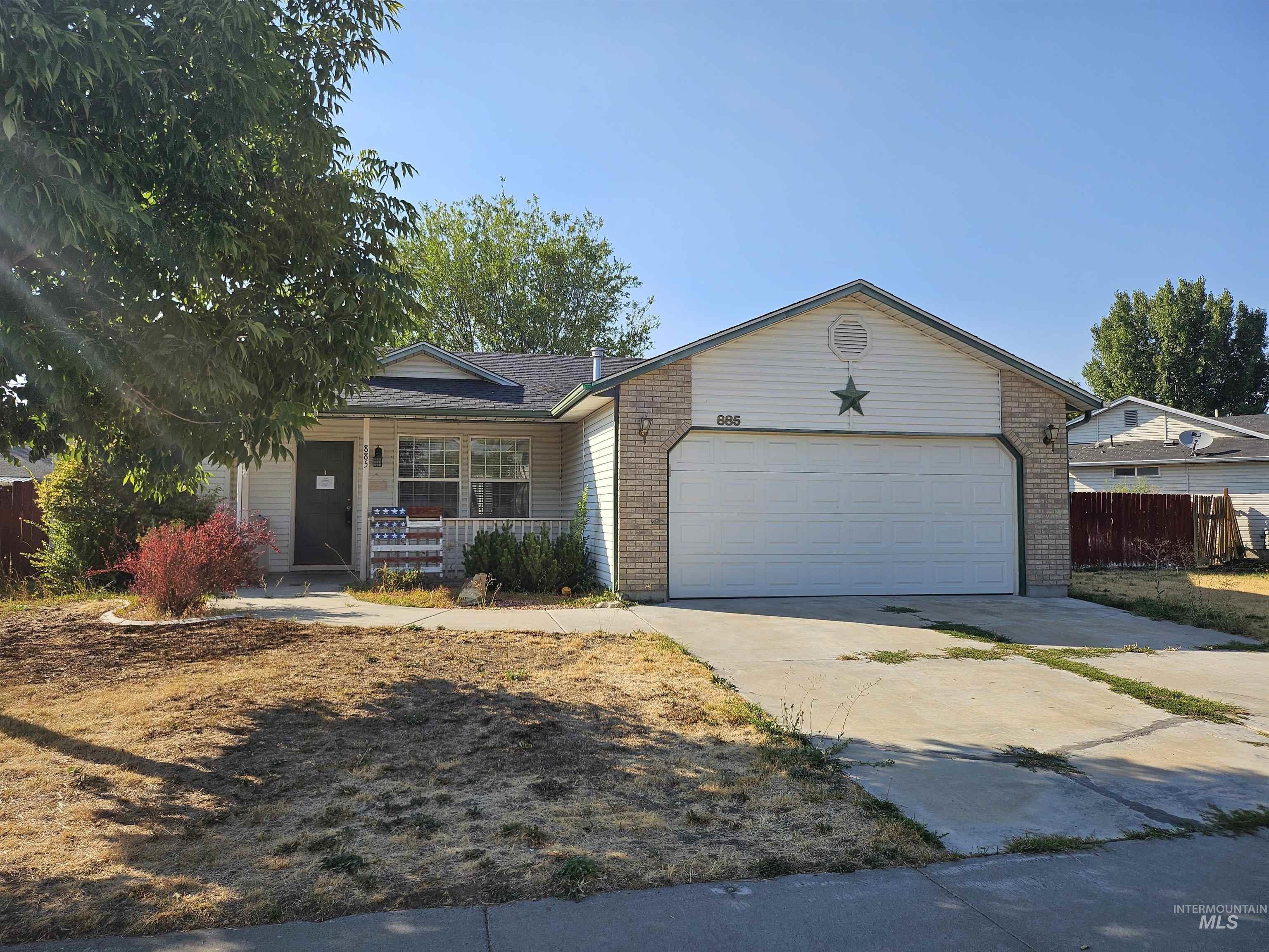 Ranch-style house with covered porch, driveway, brick siding, and a garage