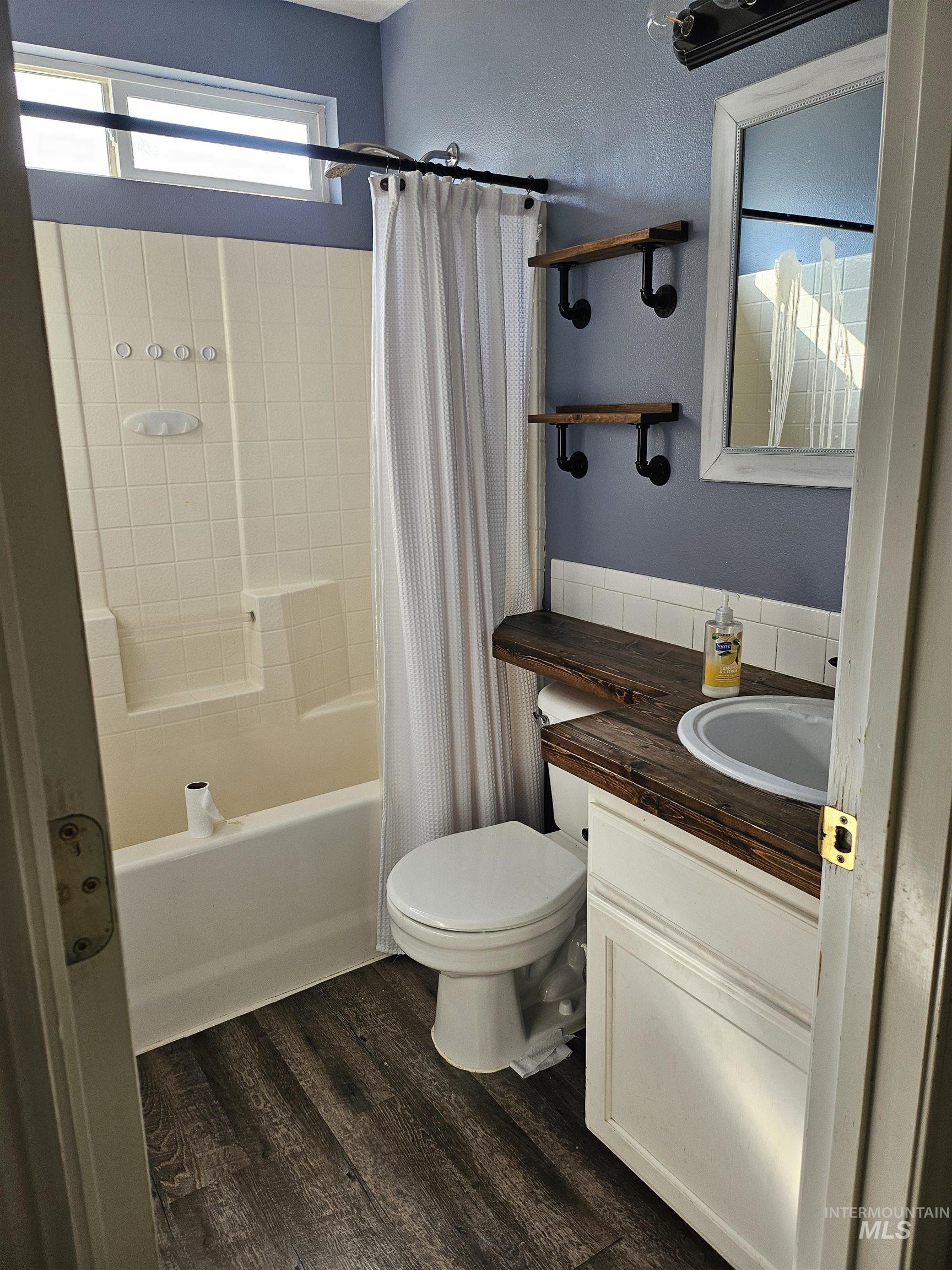 Bathroom featuring vanity, shower / tub combo, and dark wood-style floors