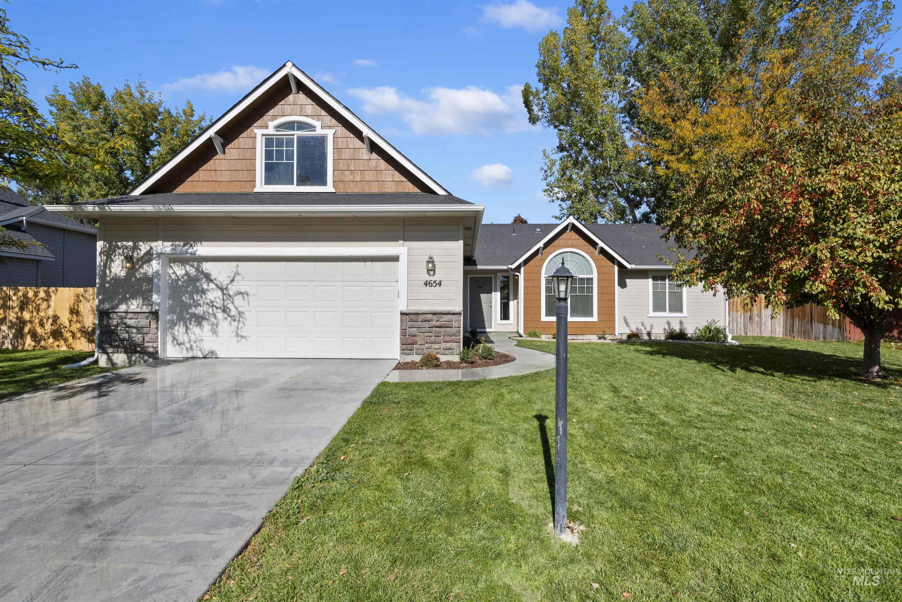 Craftsman house featuring stone siding, driveway, a front lawn, and a garage