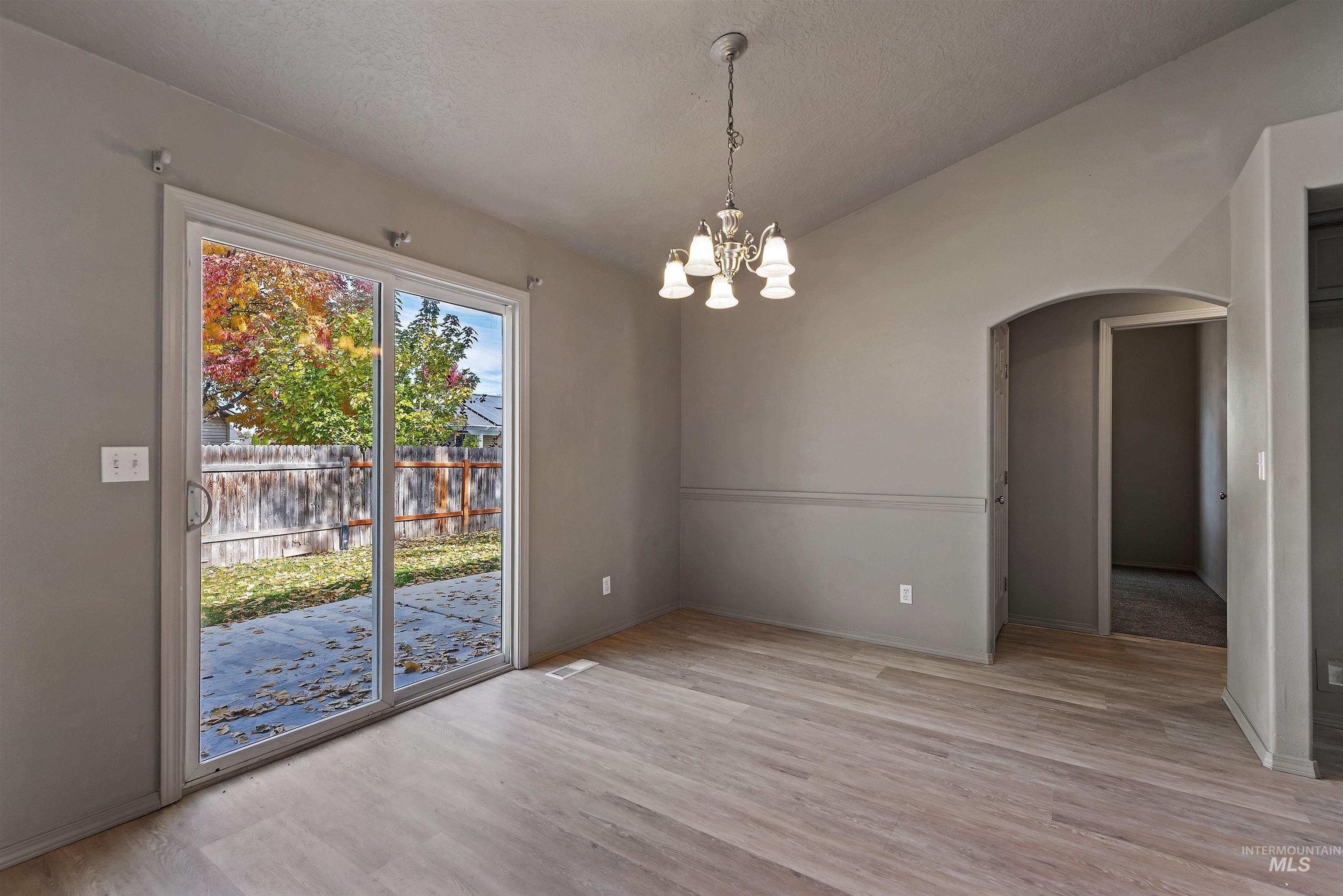 Unfurnished dining area featuring light wood finished floors, a chandelier, and arched walkways