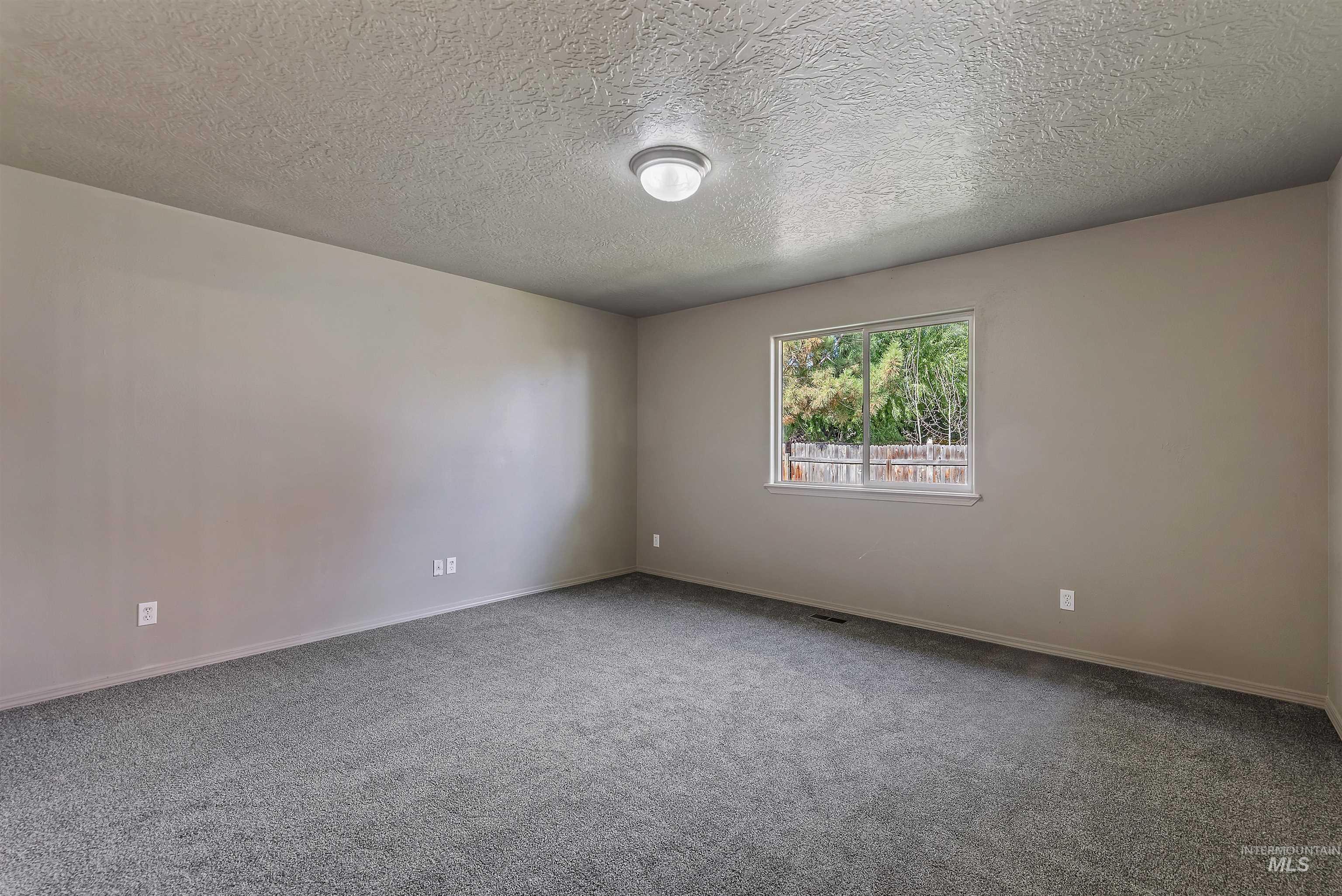 Unfurnished room featuring light carpet and a textured ceiling