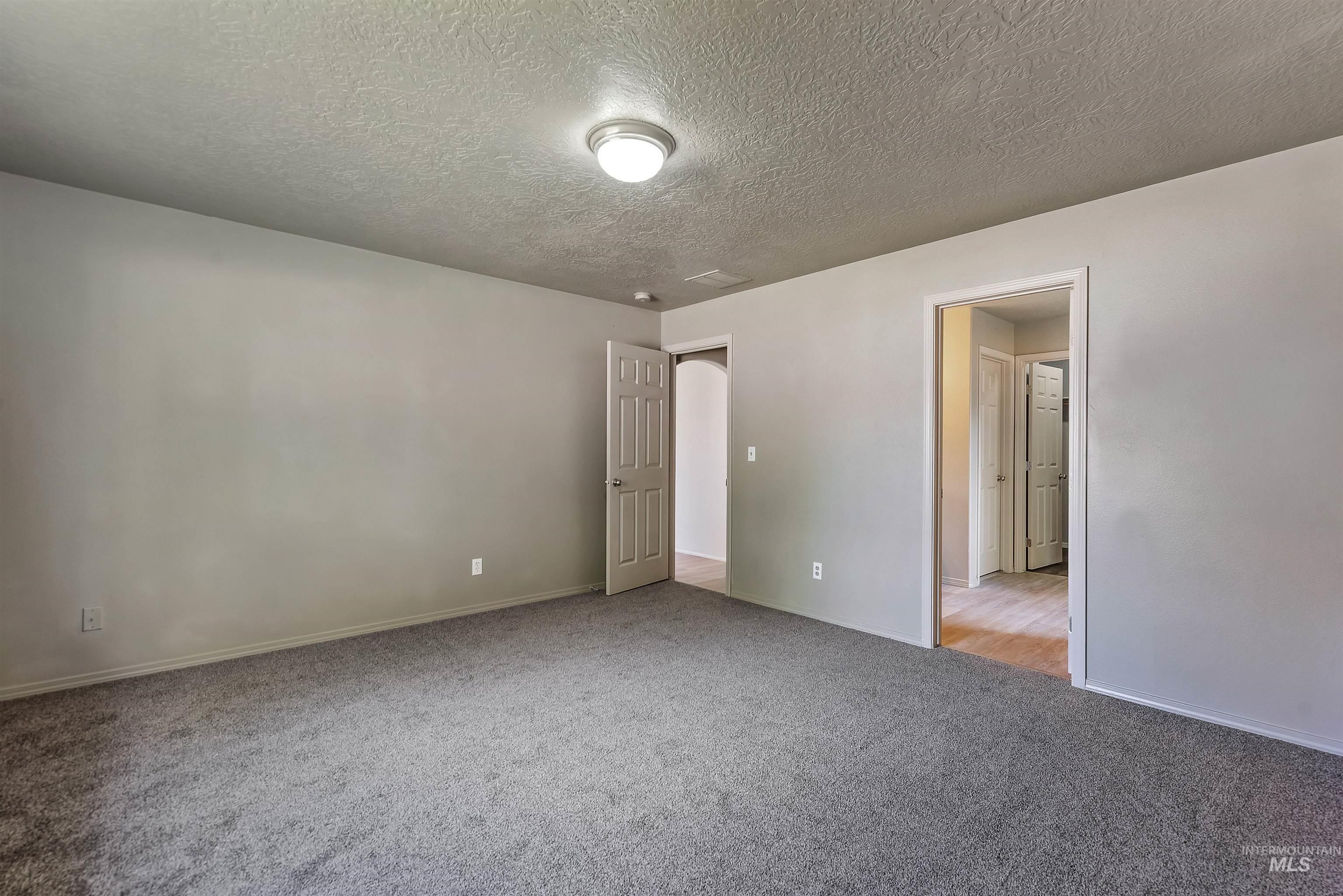 Unfurnished bedroom with a textured ceiling and light colored carpet