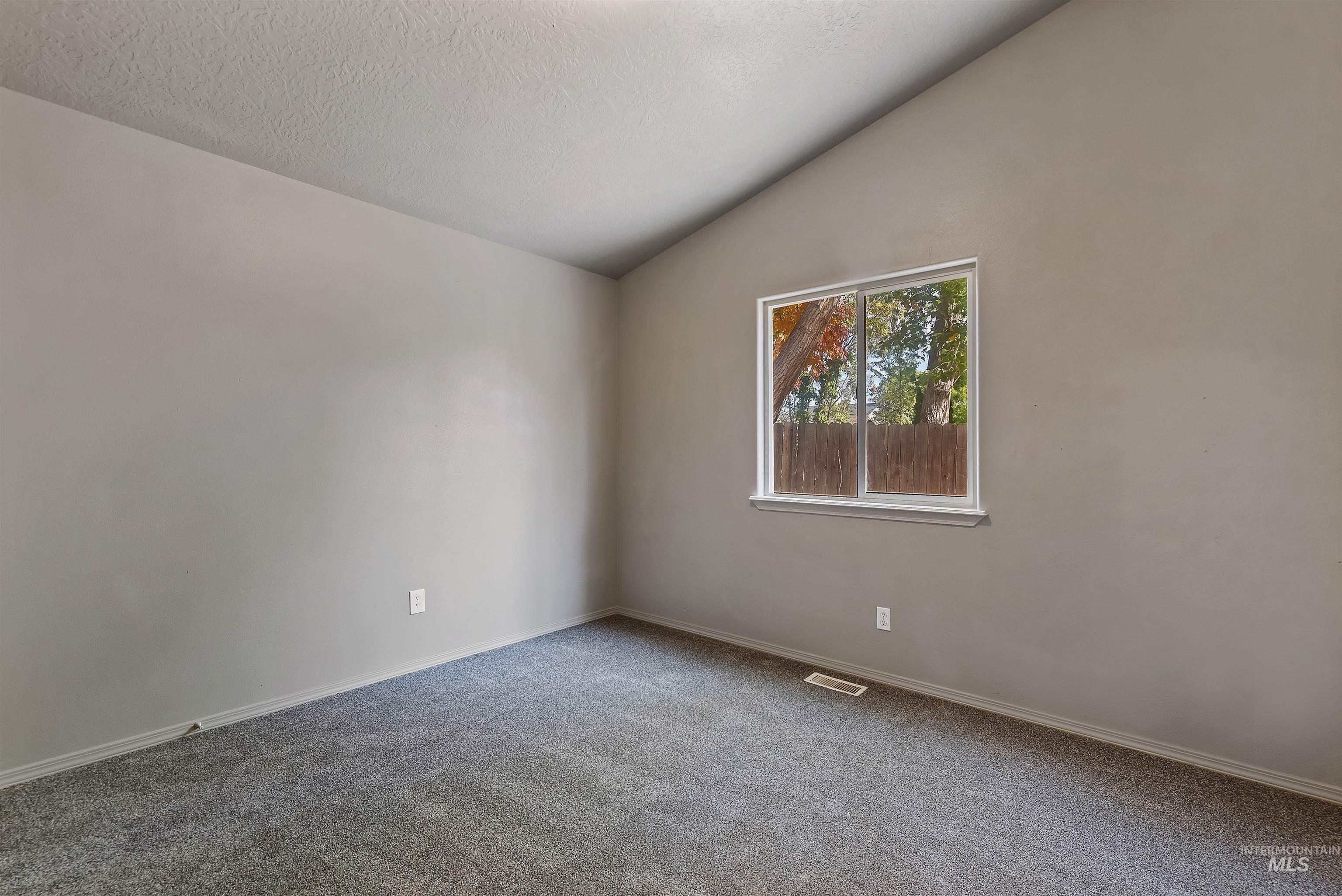 Spare room with lofted ceiling, carpet floors, and a textured ceiling
